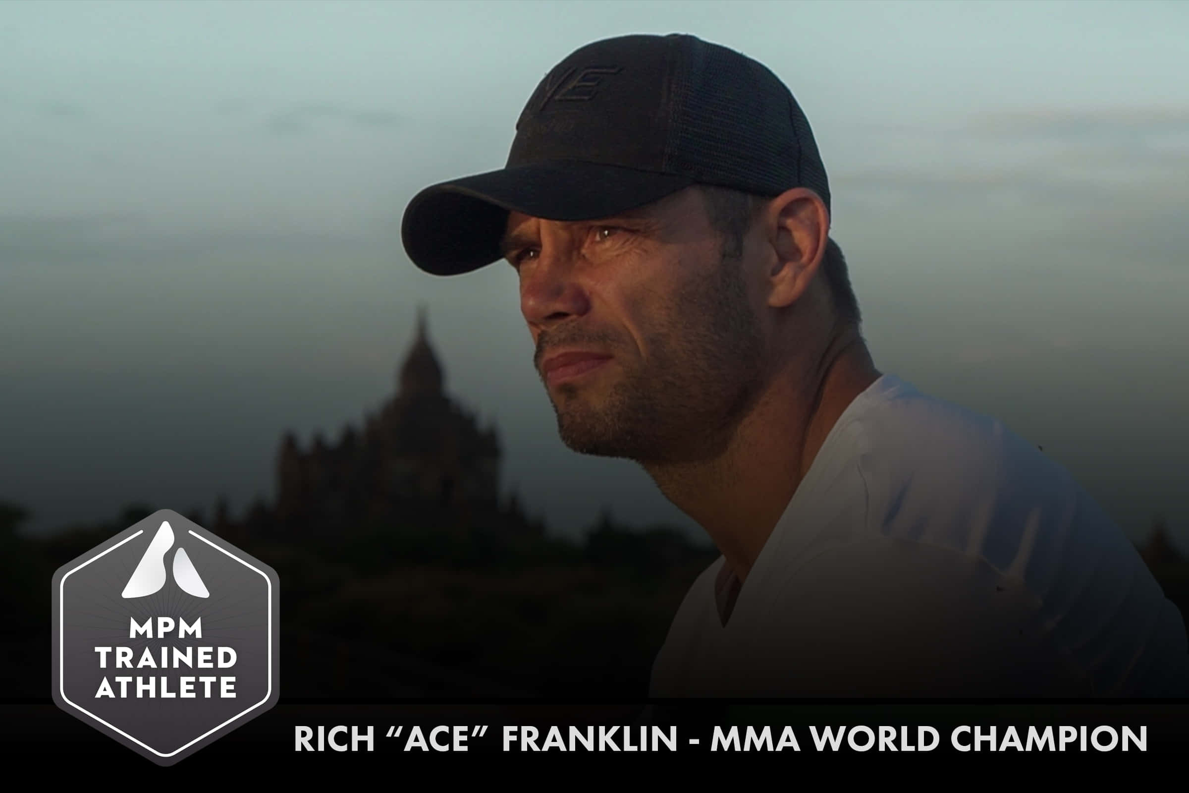 UFC 桌布 壁紙 — 一位專注的MMA冠軍戴著帽子，在暮色中若有所思地凝視著霧氣籠罩的寺廟輪廓。