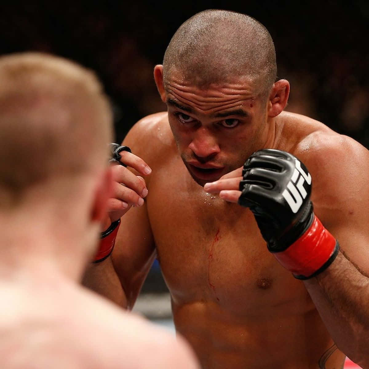 UFC 桌布 壁紙 — 一位專注的MMA拳手，胸口有血，在擂台上凝視著對手。
