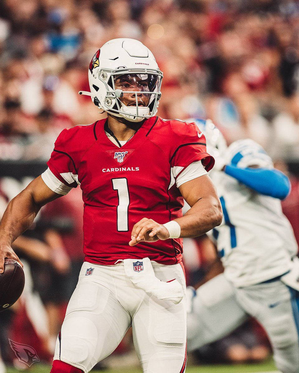 Arizona Cardinals 桌布 壁紙 — 一位專注的NFL四分衛，身穿紅色紅雀隊一號球衣，在體育場燈光下準備在比賽中擲出橄欖球。