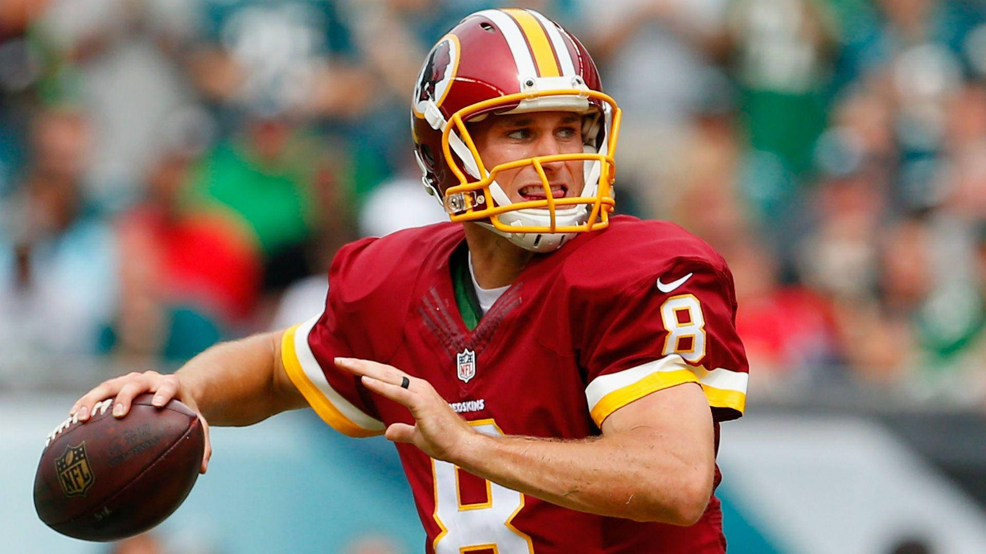運動 桌布 壁紙 — 一位專注的NFL四分衛，身穿紅色球衣背號8，在日間比賽中準備擲出橄欖球。