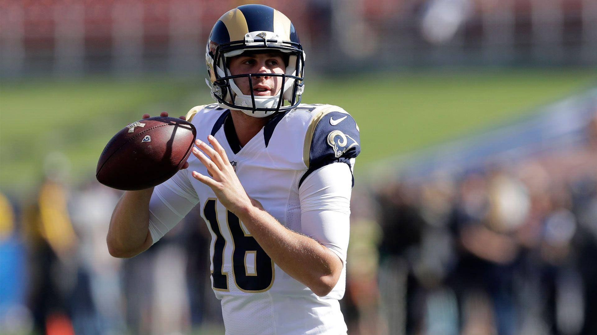 運動 桌布 壁紙 — 一位專注的NFL四分衛身穿白色公羊隊球衣，在日間比賽中準備擲出橄欖球。