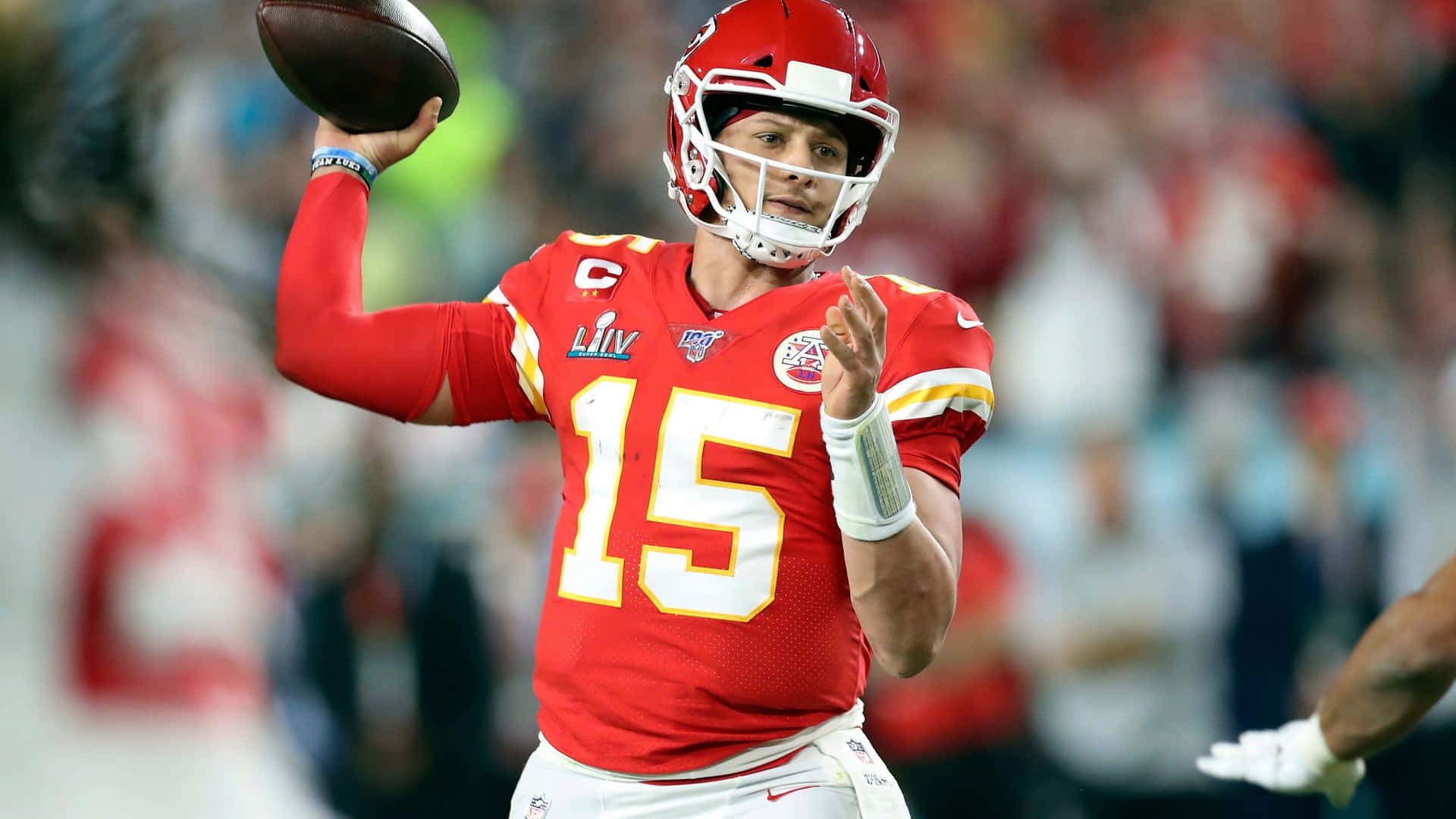 身穿紅色球衣的NFL四分衛在夜間比賽中擲出美式足球。 — 派翠克·馬霍姆斯 GIF 壁紙
