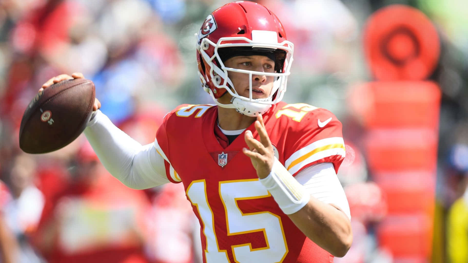 NFL四分衛身穿紅色球衣在日間比賽中擲出橄欖球。 — 派翠克·馬霍姆斯 GIF 壁紙
