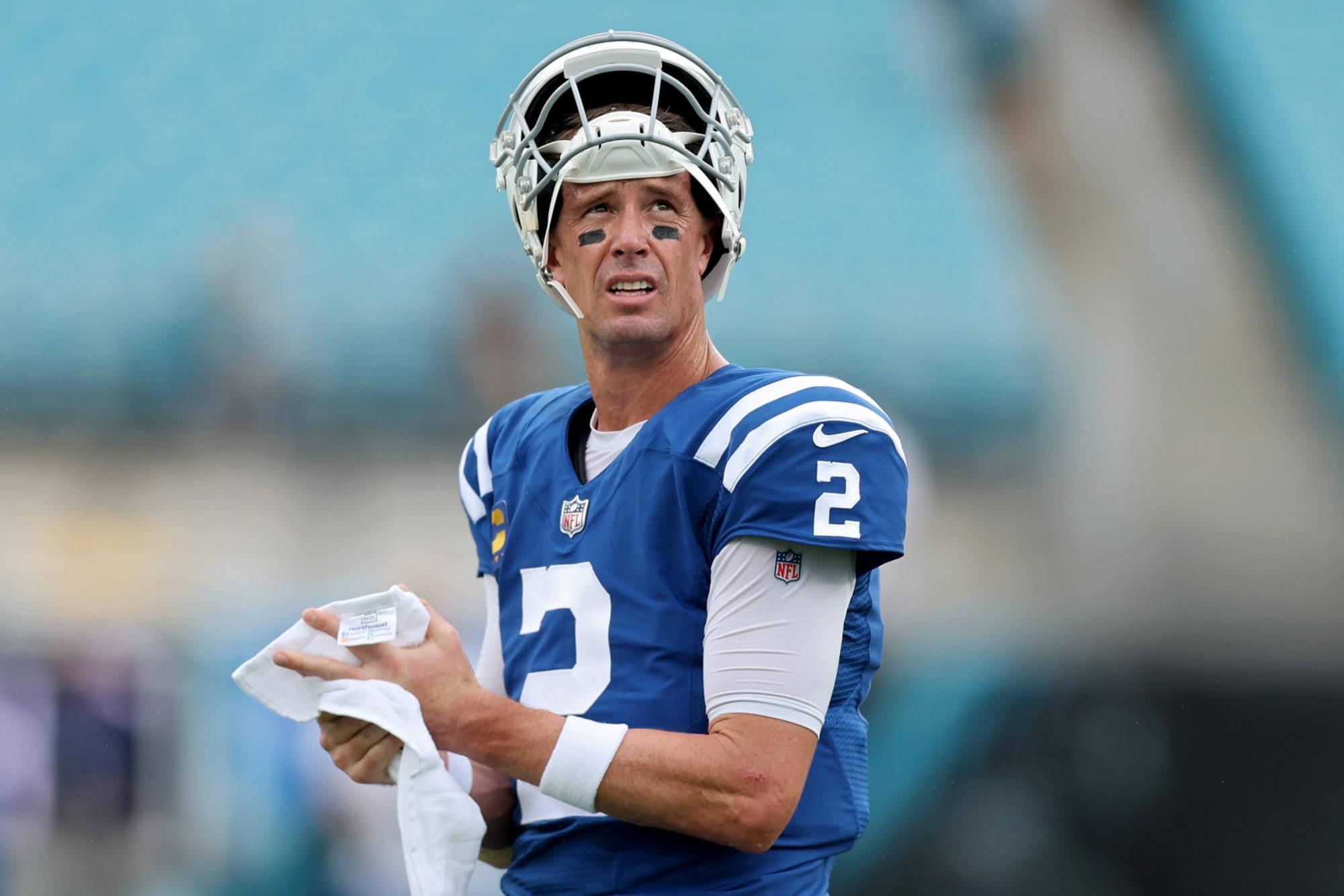 Matt Ryan 桌布 壁紙 — 一位專注的NFL四分衛身穿藍色球衣，背號二號，在比賽中用毛巾擦臉。