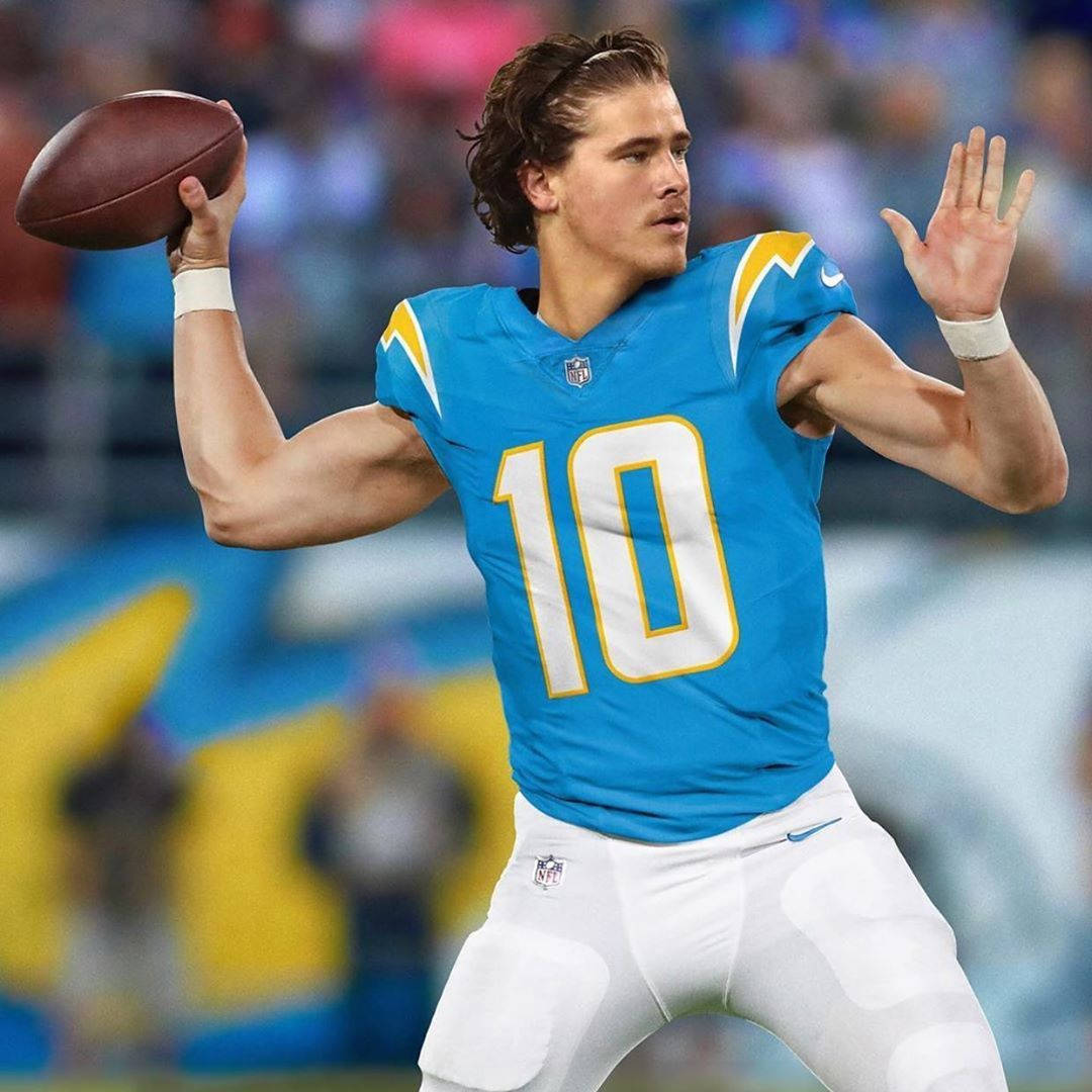 Herbert 桌布 壁紙 — 一位專注的NFL四分衛身穿藍色球衣，號碼10，在體育場燈光下準備在比賽中傳球。