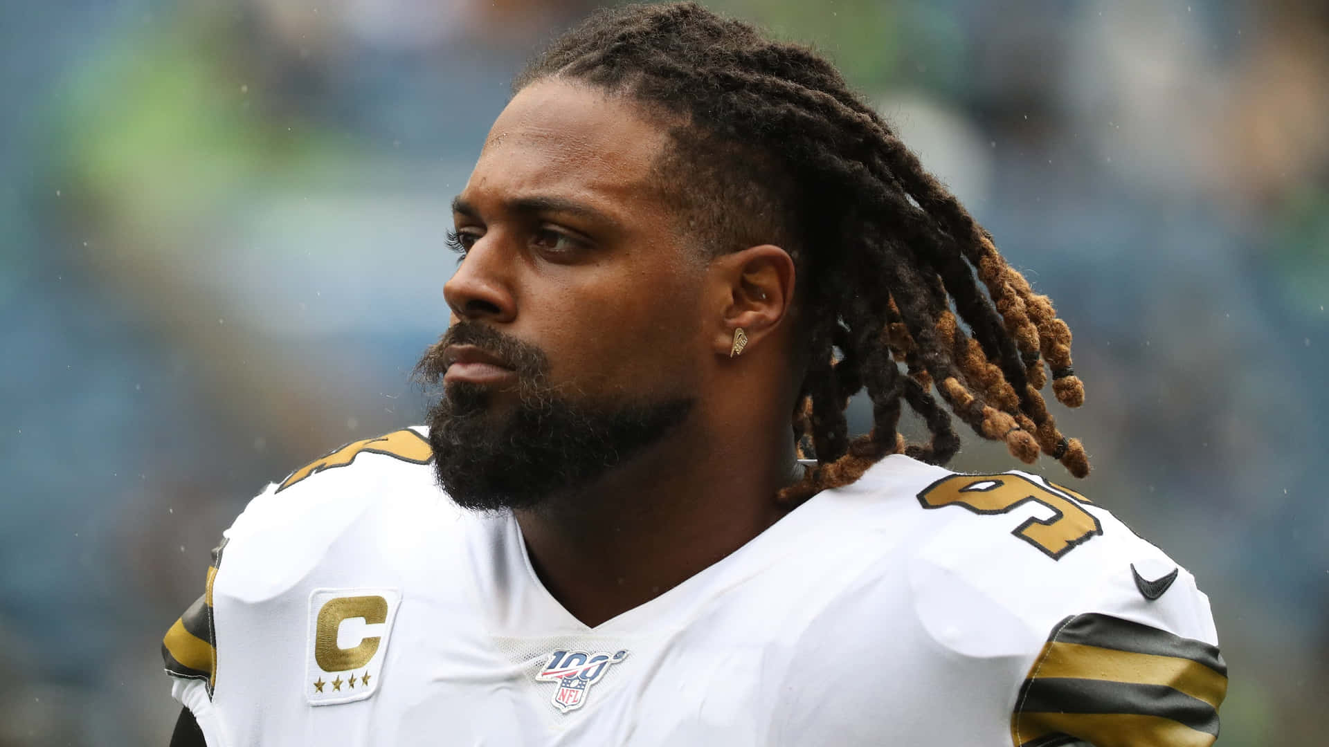 NFL美式足球員在雨中穿著帶有隊長臂章的白金色制服。 — Michael B Jordan 壁紙