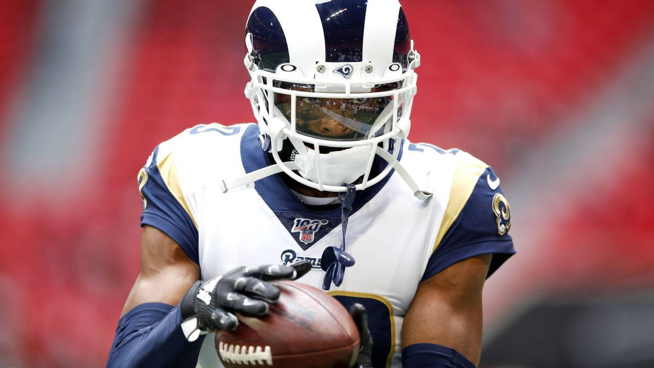 Ramsey 桌布 壁紙 — 一位專注的NFL球員身穿白色和藍色的公羊隊制服，在體育場燈光下緊緊抓住橄欖球。