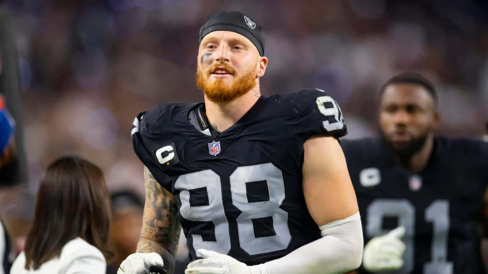 運動 桌布 壁紙 — 一位專注的NFL防守端鋒，留著紅色鬍鬚，身穿黑色98號球衣，在體育場燈光下比賽時站在場上。