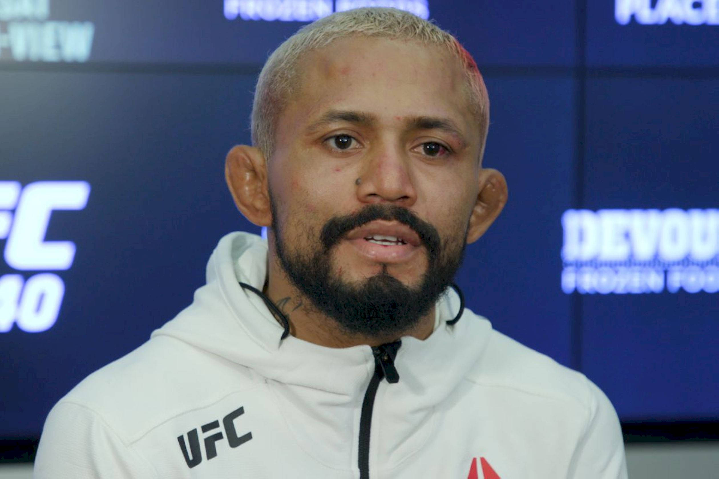 UFC 桌布 壁紙 — 一位專注的UFC拳手，留鬍鬚、剃光頭，在記者會上穿著白色連帽衫。