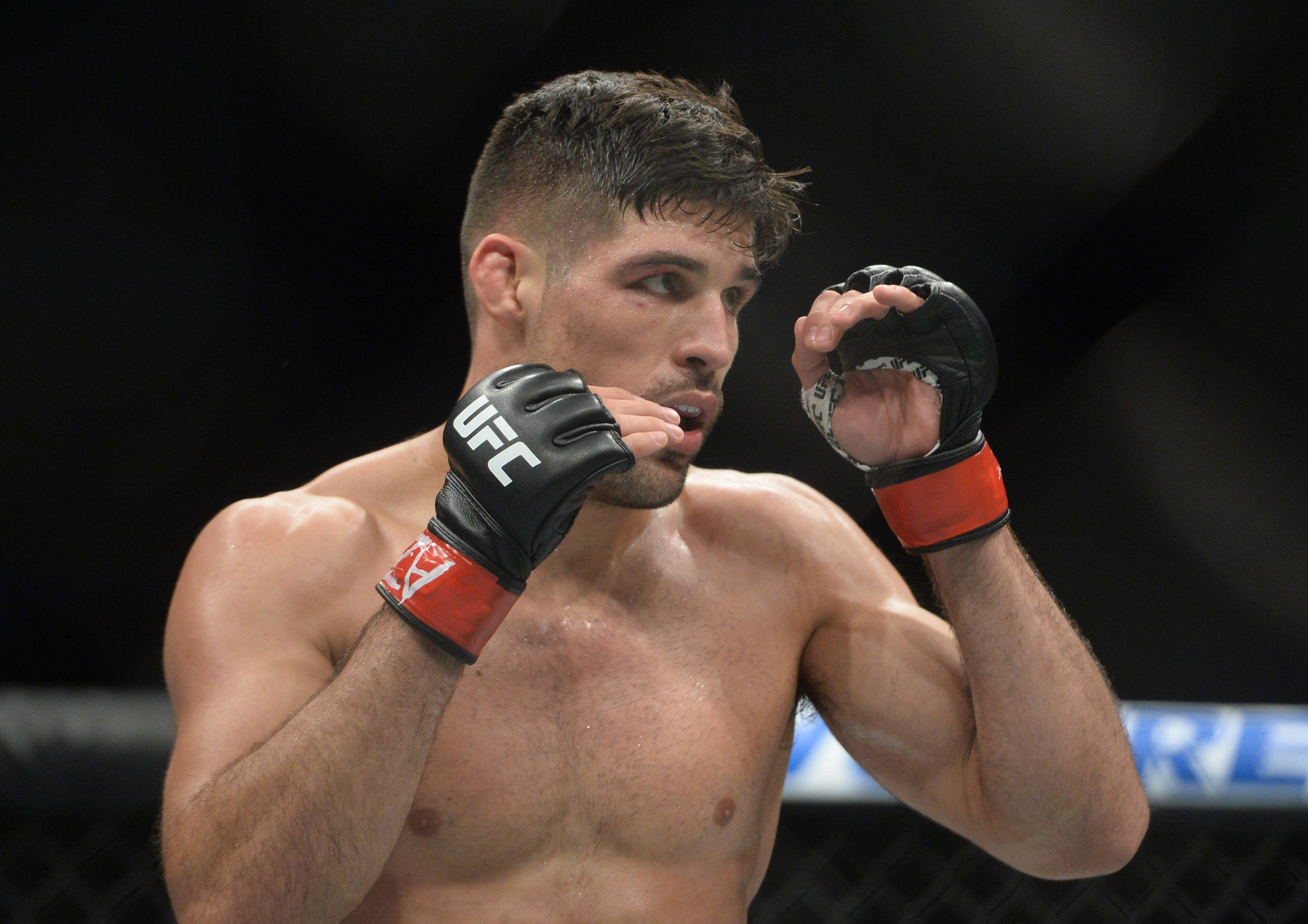 UFC 桌布 壁紙 — 一位專注的UFC拳擊手戴著黑色和紅色手套，帶著強烈的決心在八角籠中準備就緒。