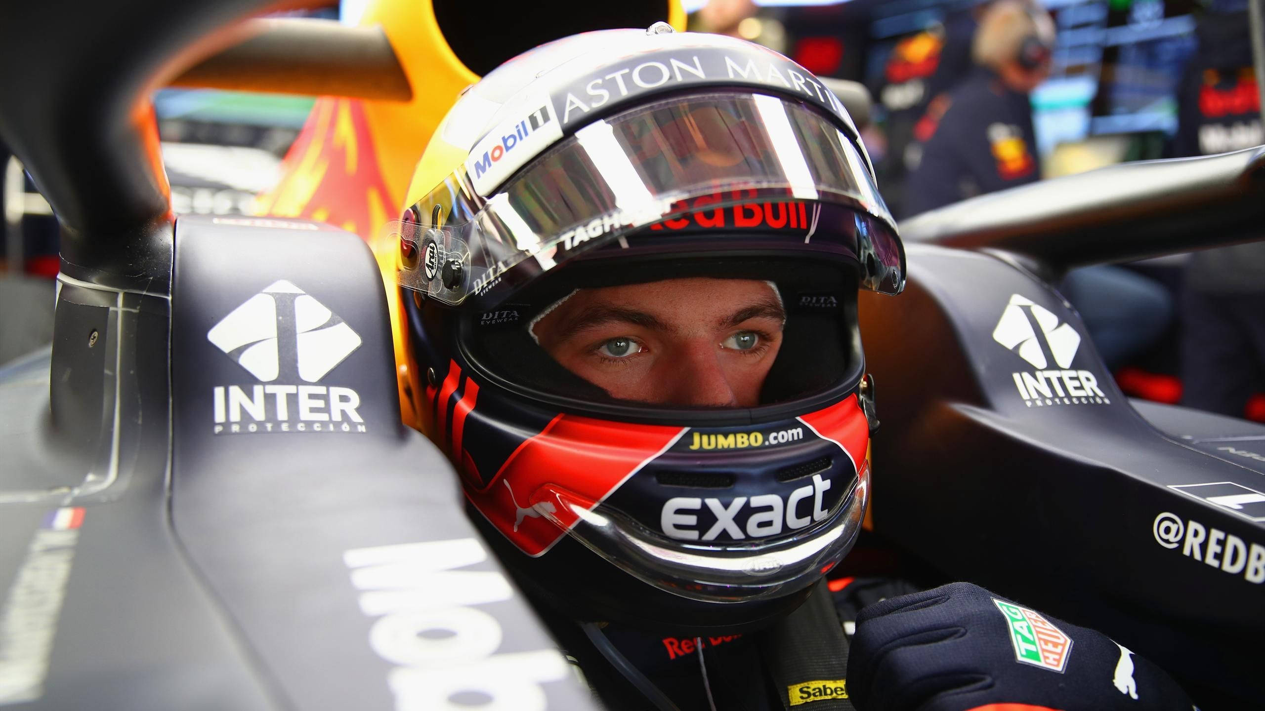 Verstappen 桌布 壁紙 — 一位專注的一級方程式車手，戴著紅黑頭盔，從他的阿斯頓馬丁賽車內部凝視著。