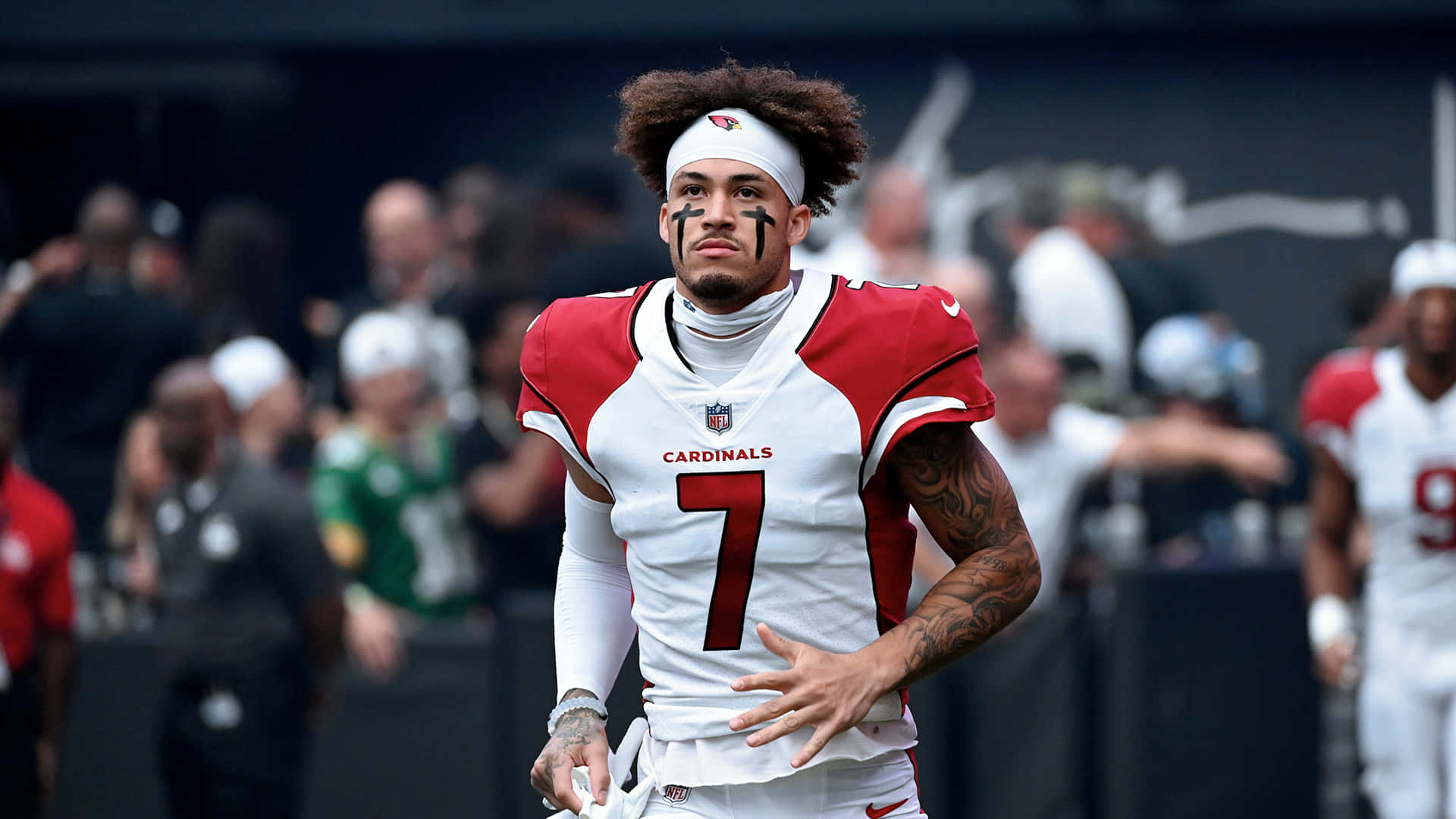 Byron Murphy 桌布 壁紙 — 一位專注的亞利桑那紅雀隊美式足球員身穿7號球衣，臉上塗有黑色顏料並戴著白色頭帶站在球場上。