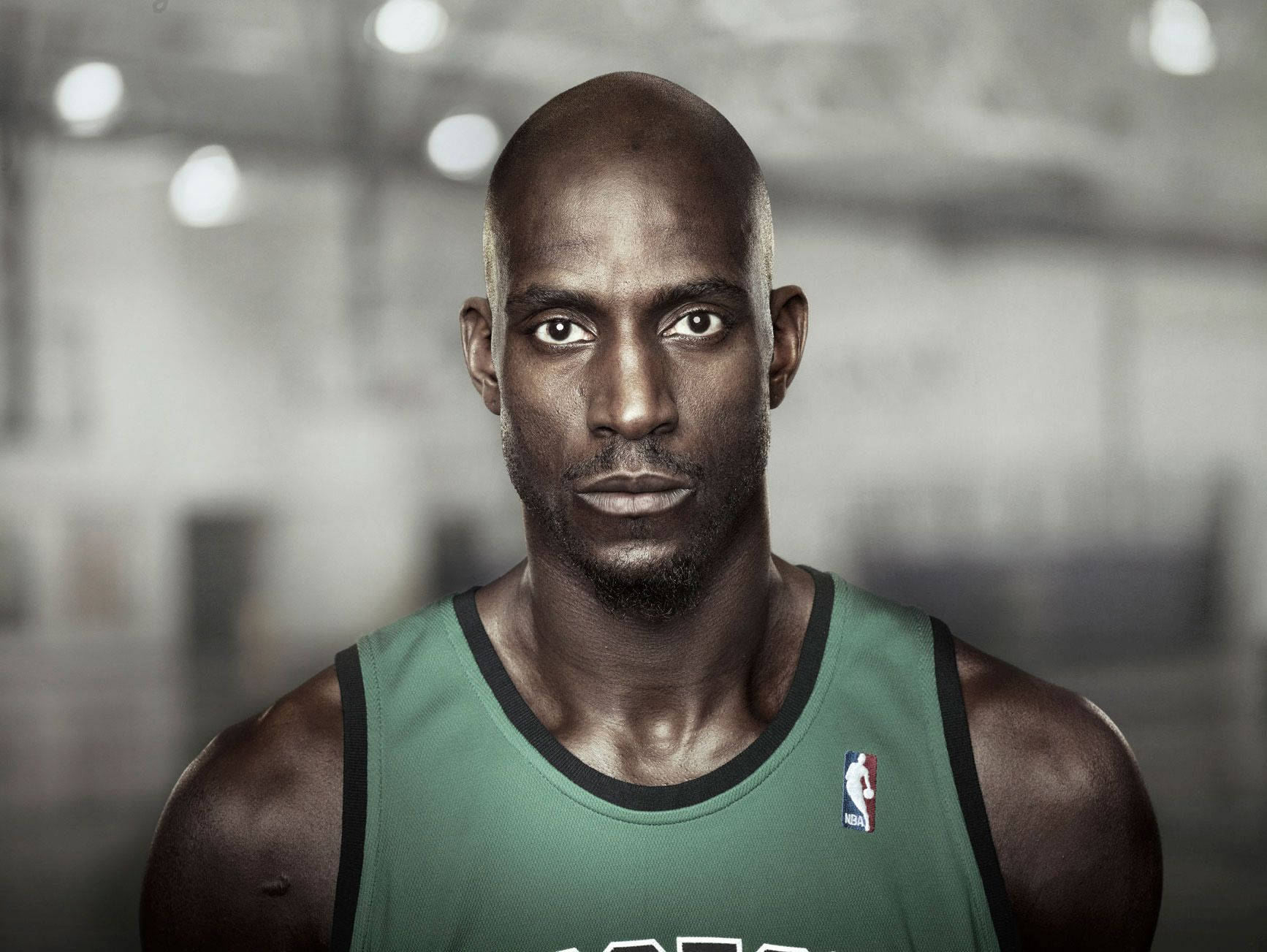 Kevin Garnett 桌布 壁紙 — 一位專注的光頭籃球運動員穿著綠色球衣，在健身房環境中強烈地凝視著鏡頭。