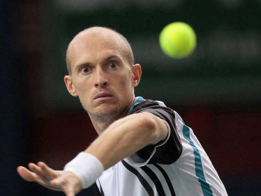 Tennis 桌布 壁紙 — 一位專注的光頭網球選手向前猛衝，以強烈的專注力擊中空中一顆亮黃色的網球。