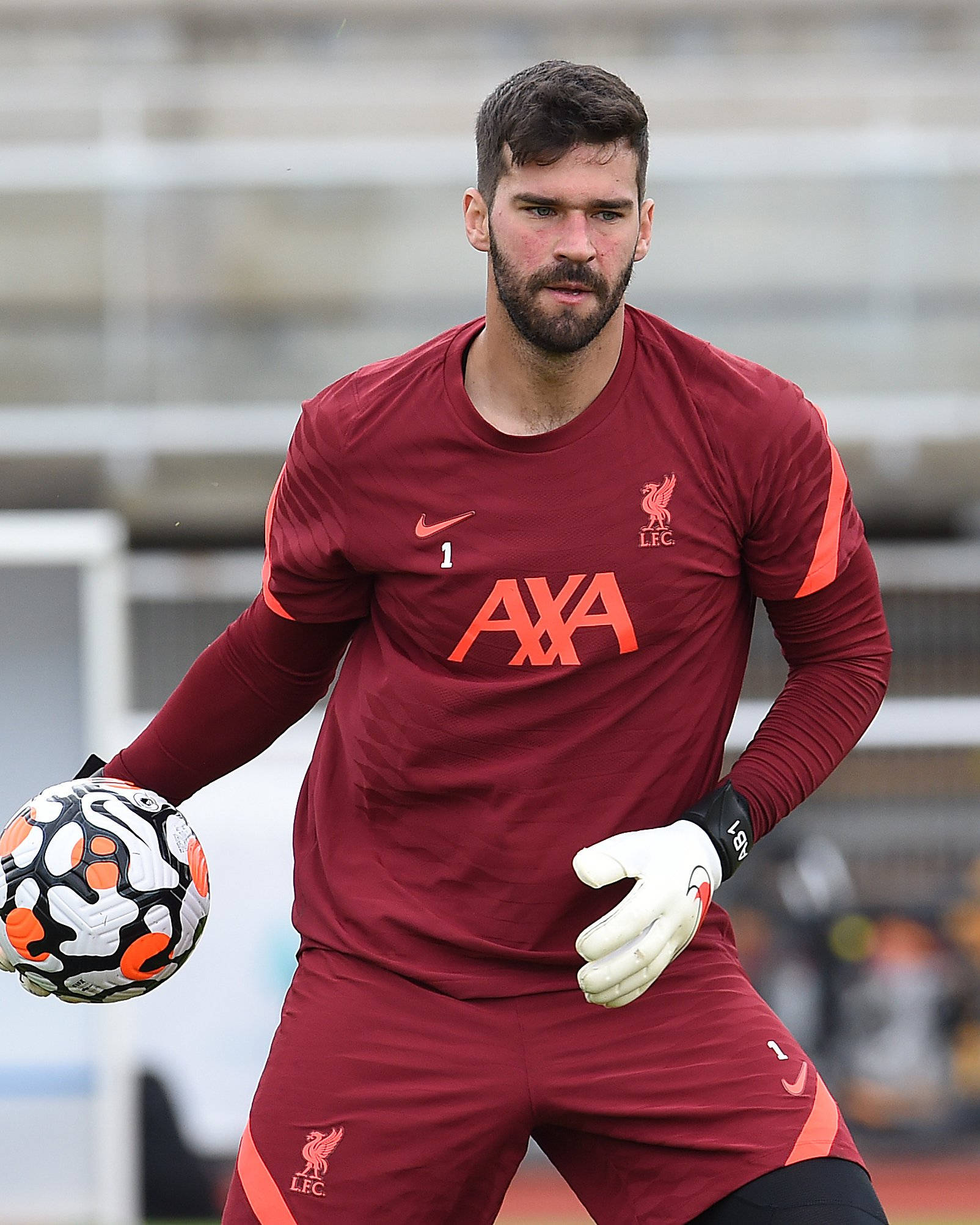 Alisson Becker 桌布 壁紙 — 一位專注的利物浦FC門將身穿栗色球衣在球場訓練時手持足球。