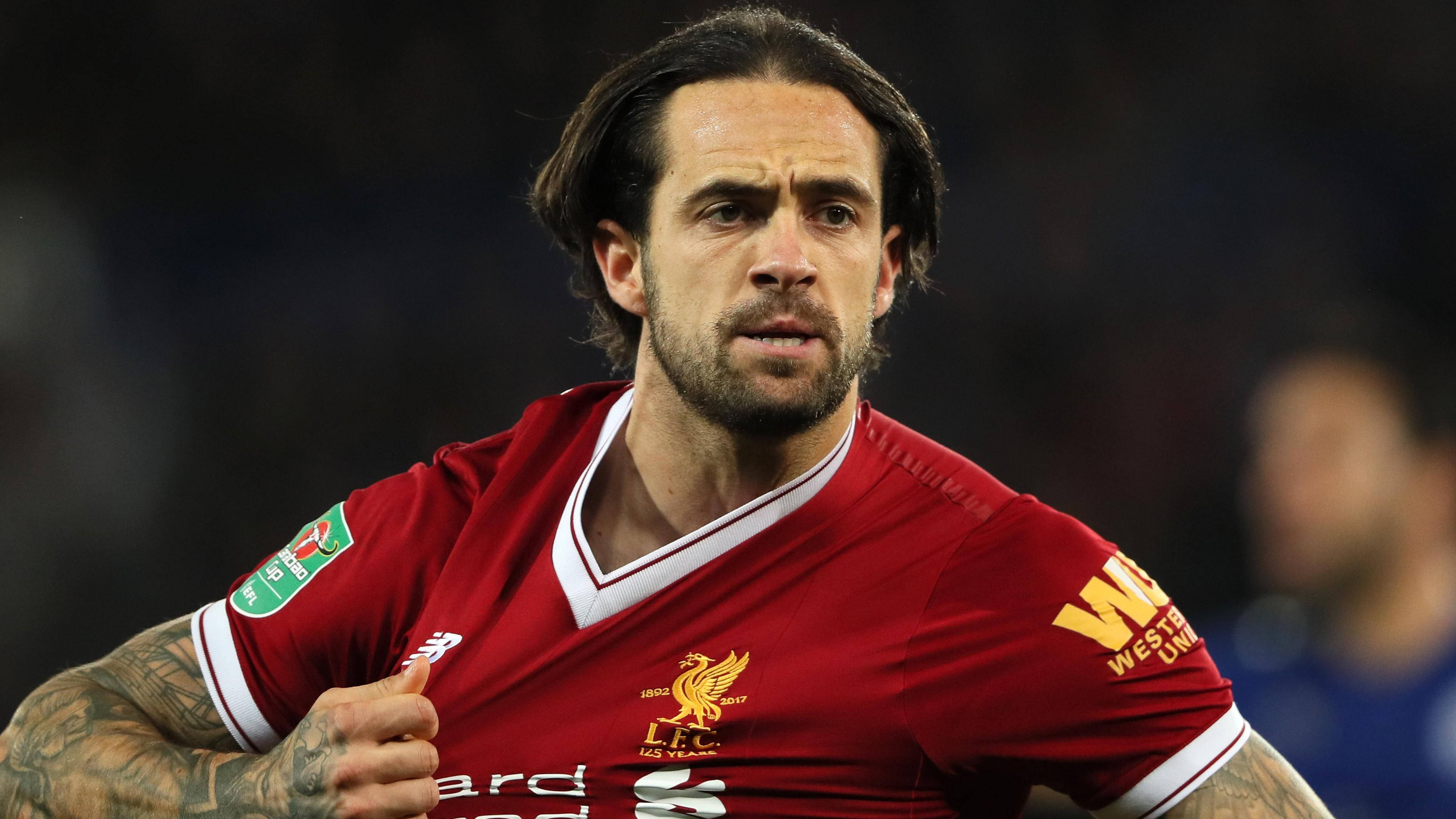 Football Players 桌布 壁紙 — 一位專注的利物浦足球員身穿紅色球衣，在夜間比賽中於球場燈光下豎起大拇指。