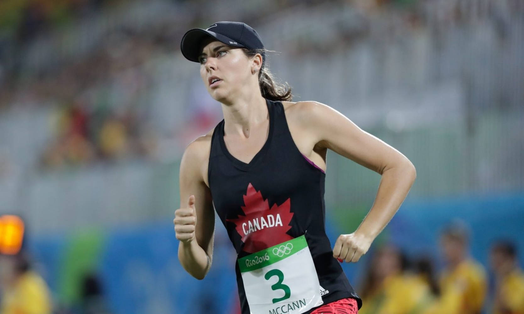 運動 桌布 壁紙 — 一位專注的加拿大女運動員穿著帶有紅色楓葉的黑色跑步裝備，在體育場燈光下參加里約2016奧運會。