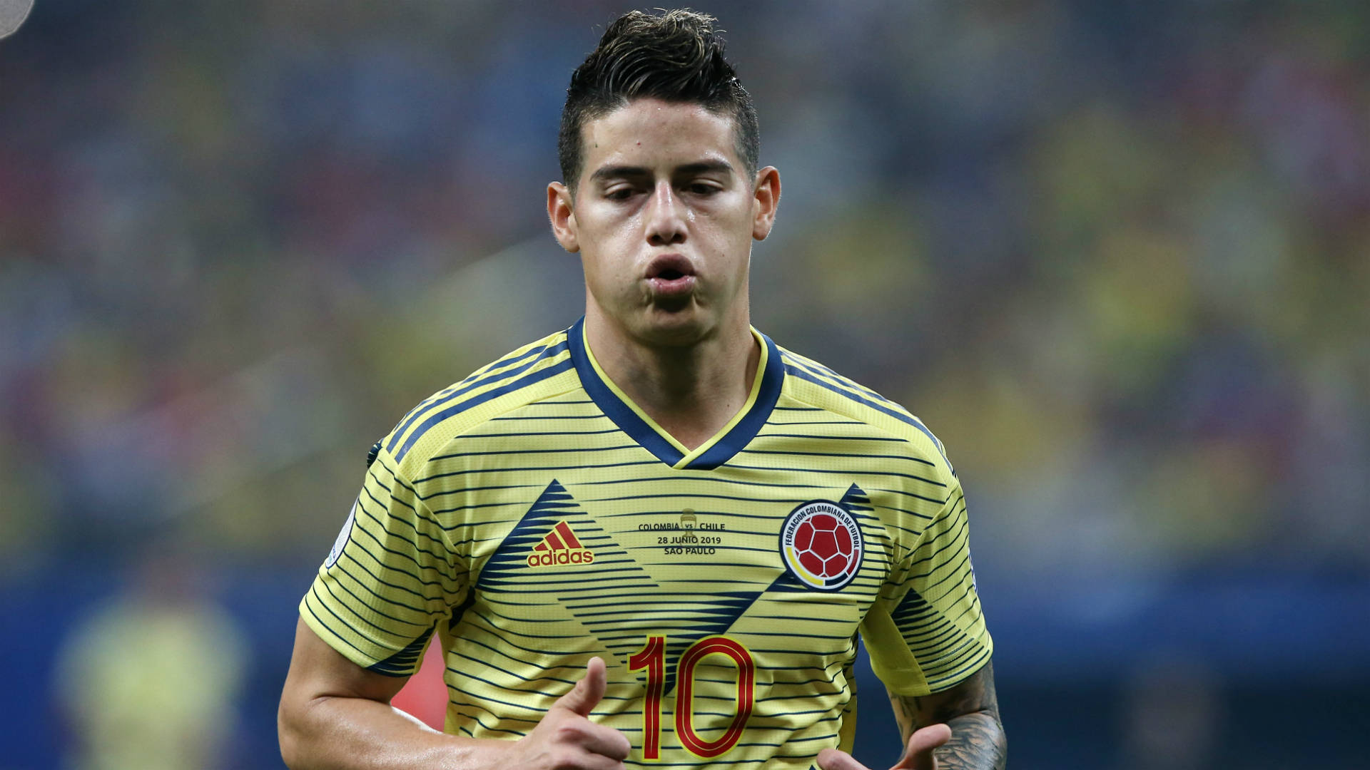 James Rodriguez 桌布 壁紙 — 一位專注的哥倫比亞足球運動員身穿黃色條紋球衣，號碼10，在體育場上奔跑。