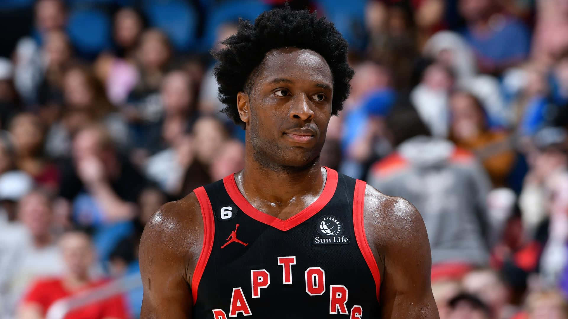 NBA 桌布 壁紙 — 一位專注的多倫多暴龍籃球員身穿黑紅球衣，站在球場上，身後是模糊的人群。