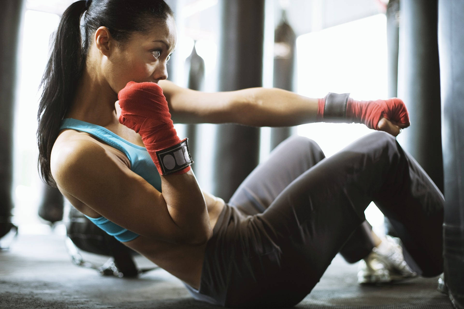 Exercise 桌布 壁紙 — 一位專注的女拳擊手，纏著紅色護手帶，在健身房進行激烈訓練時打出強力一拳。