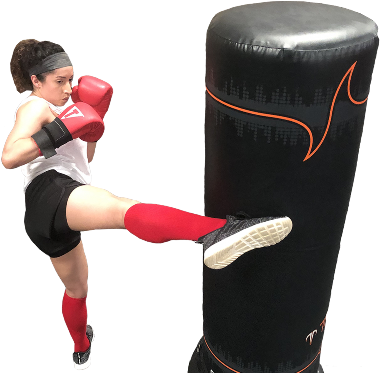 Kickboxing 桌布 壁紙 — 一位專注的女拳擊手對著一個黑色和橙色的重型沙包踢出強力一腳，背景是純黑色。