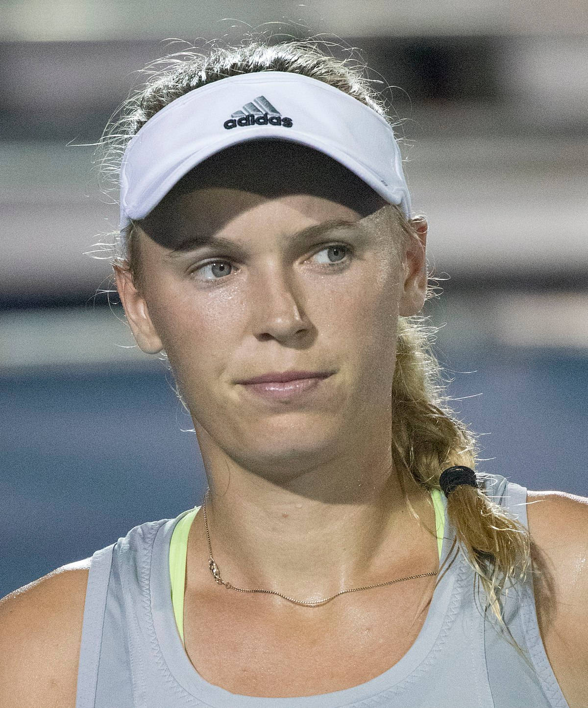 Tennis 桌布 壁紙 — 一位專注的女網球運動員，戴著白色 adidas 遮陽帽和馬尾辮，在體育館燈光下比賽時凝視著。