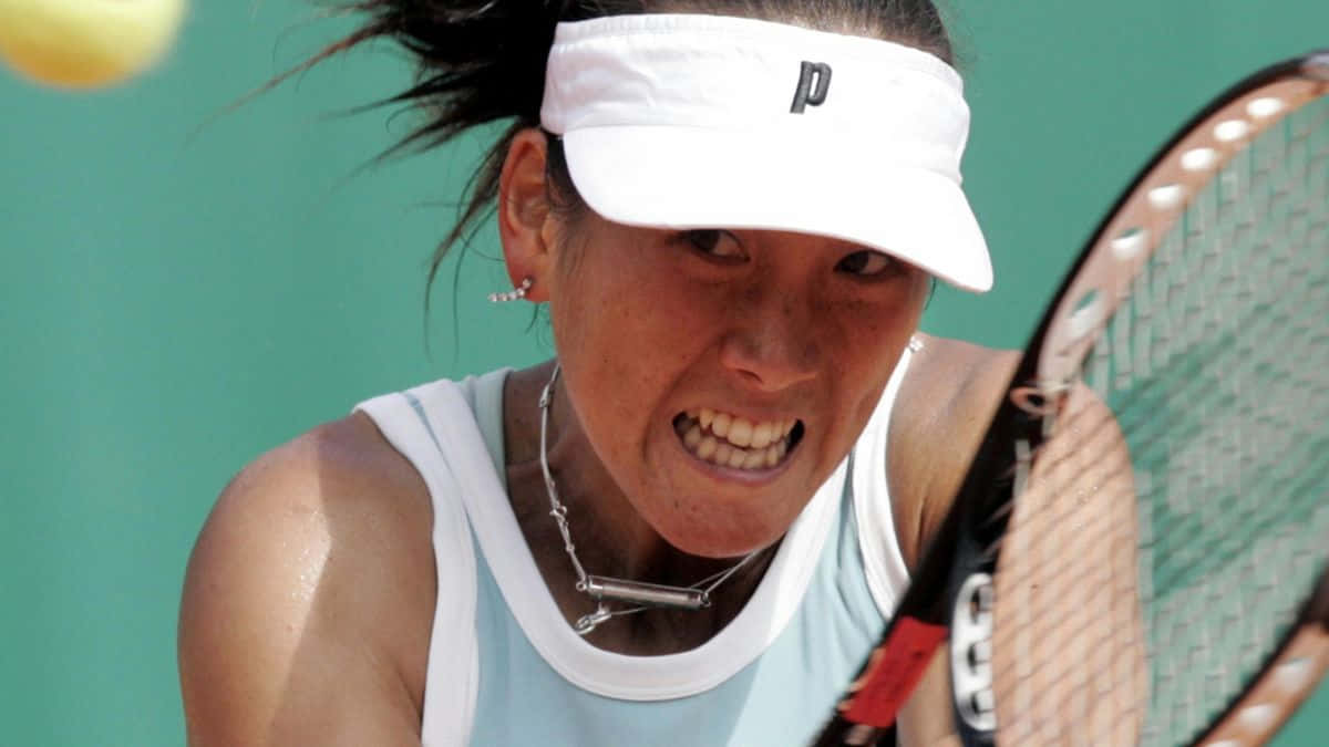 Tennis 桌布 壁紙 — 一位專注的女網球運動員在綠色球場牆壁前揮拍擊打黃色網球時，因極度專注而扭曲表情。