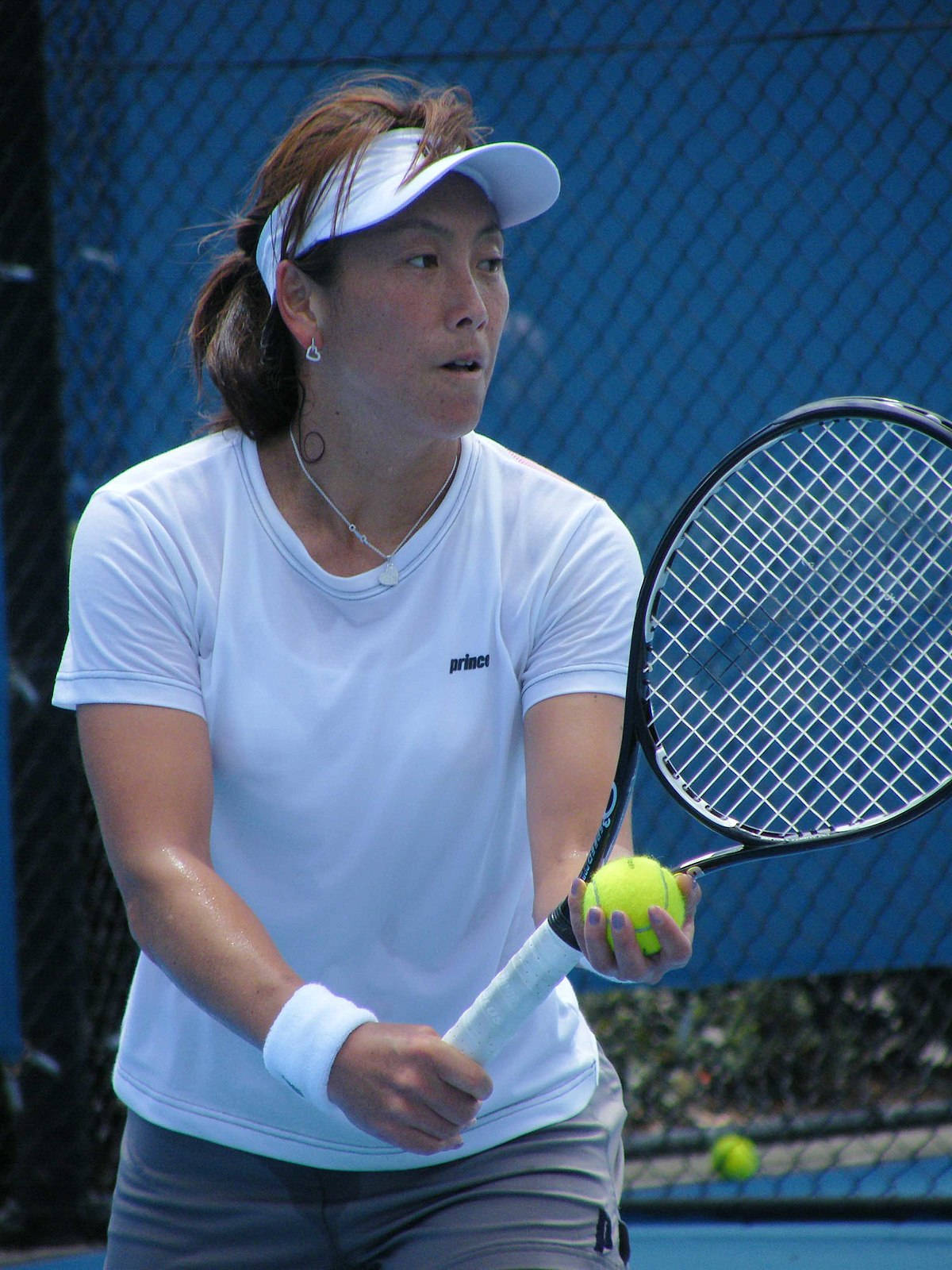 Athlete 桌布 壁紙 — 一位專注的女網球運動員穿著白色裝備，在藍色球場上於明亮的日光下握著球拍和球。