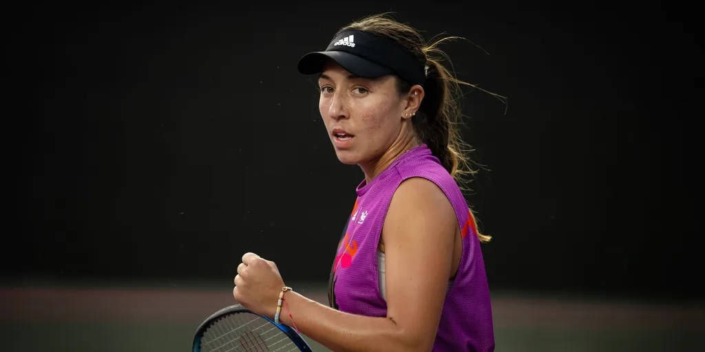 Tennis 桌布 壁紙 — 一位專注的女網球運動員穿著紫色上衣和黑色帽子，在深色背景下比賽中握著球拍。