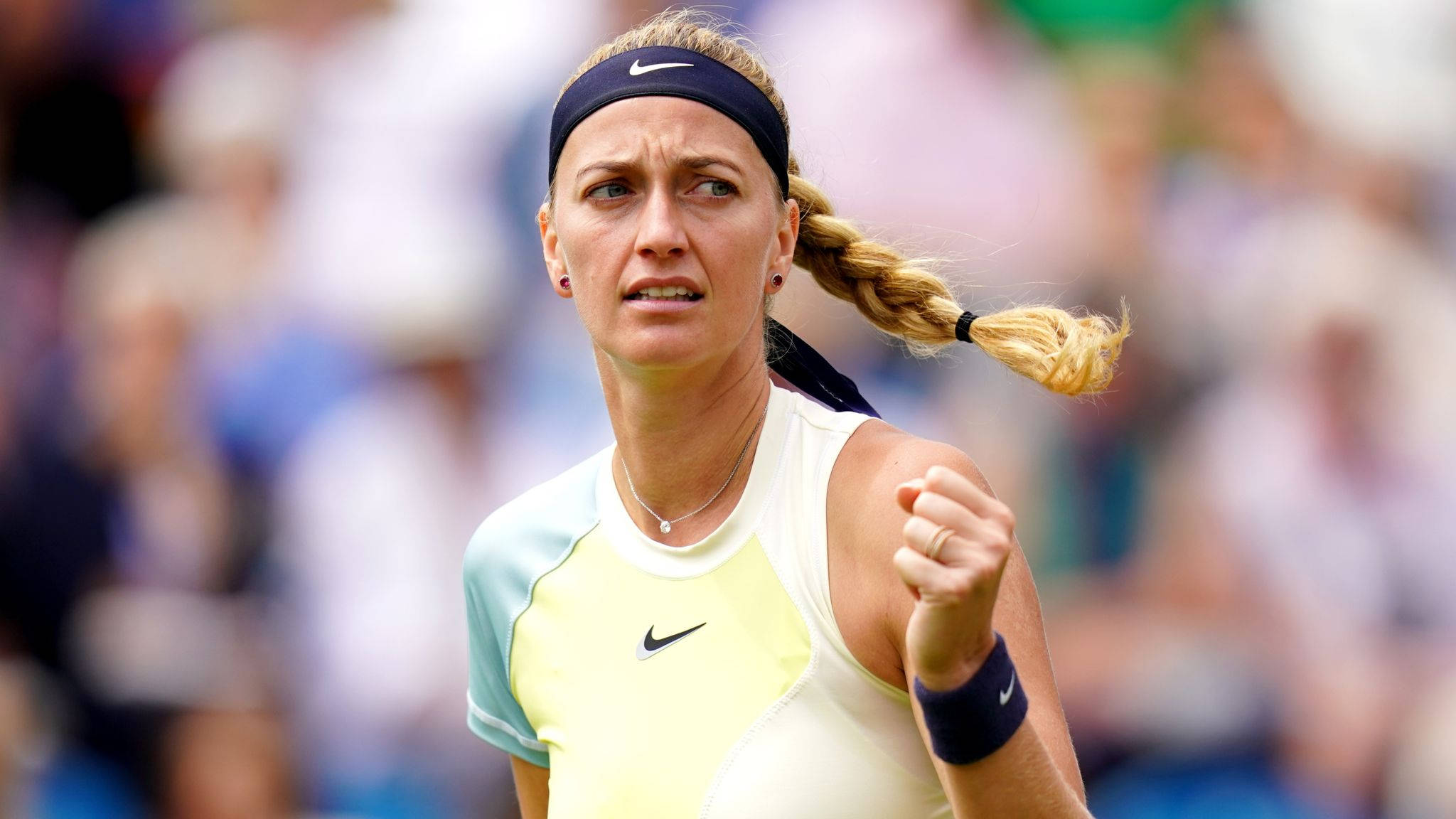 Nike 桌布 壁紙 — 一位專注的女網球運動員紮著辮子馬尾辮，在陽光明媚的球場上比賽中握緊拳頭。