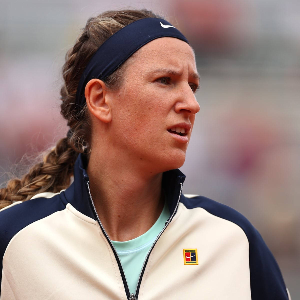 Athletic 桌布 壁紙 — 一位專注的女網球選手，梳著辮子馬尾，戴著海軍藍頭帶，在比賽中凝視著。