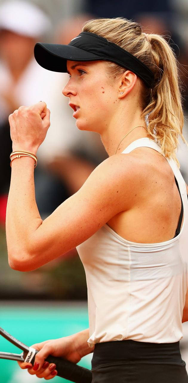 Elina Svitolina 桌布 壁紙 — 一位專注的女網球選手在明亮的日光下於紅土球場上握緊拳頭，充滿決心。