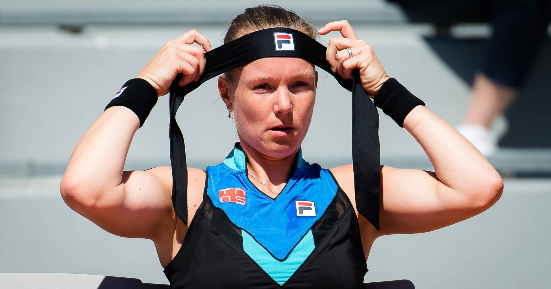 Tennis 桌布 壁紙 — 一位專注的女網球選手在明亮的日光下調整她的黑色頭帶。