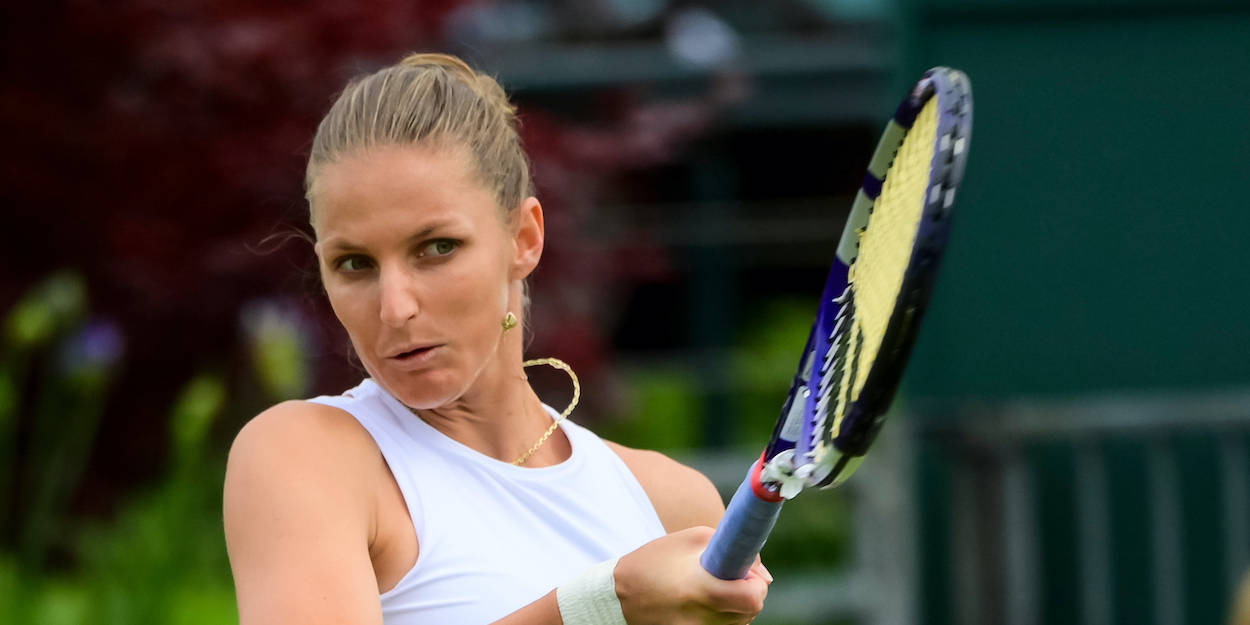 Tennis 桌布 壁紙 — 一位專注的女網球選手在模糊的綠色和紅色樹葉背景下揮拍中握緊球拍。