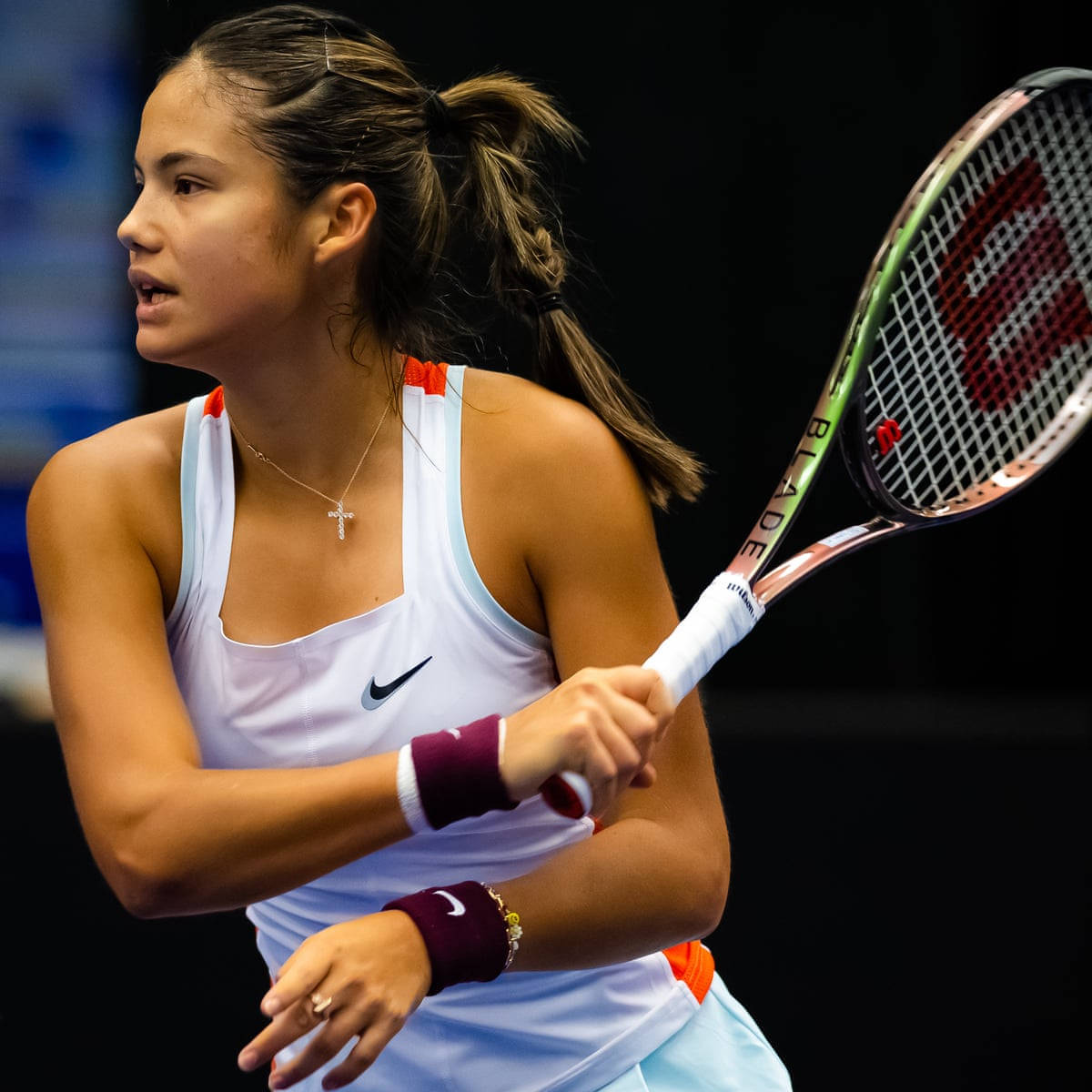 Athletic 桌布 壁紙 — 一位專注的女網球選手在深色背景下揮動Wilson球拍。