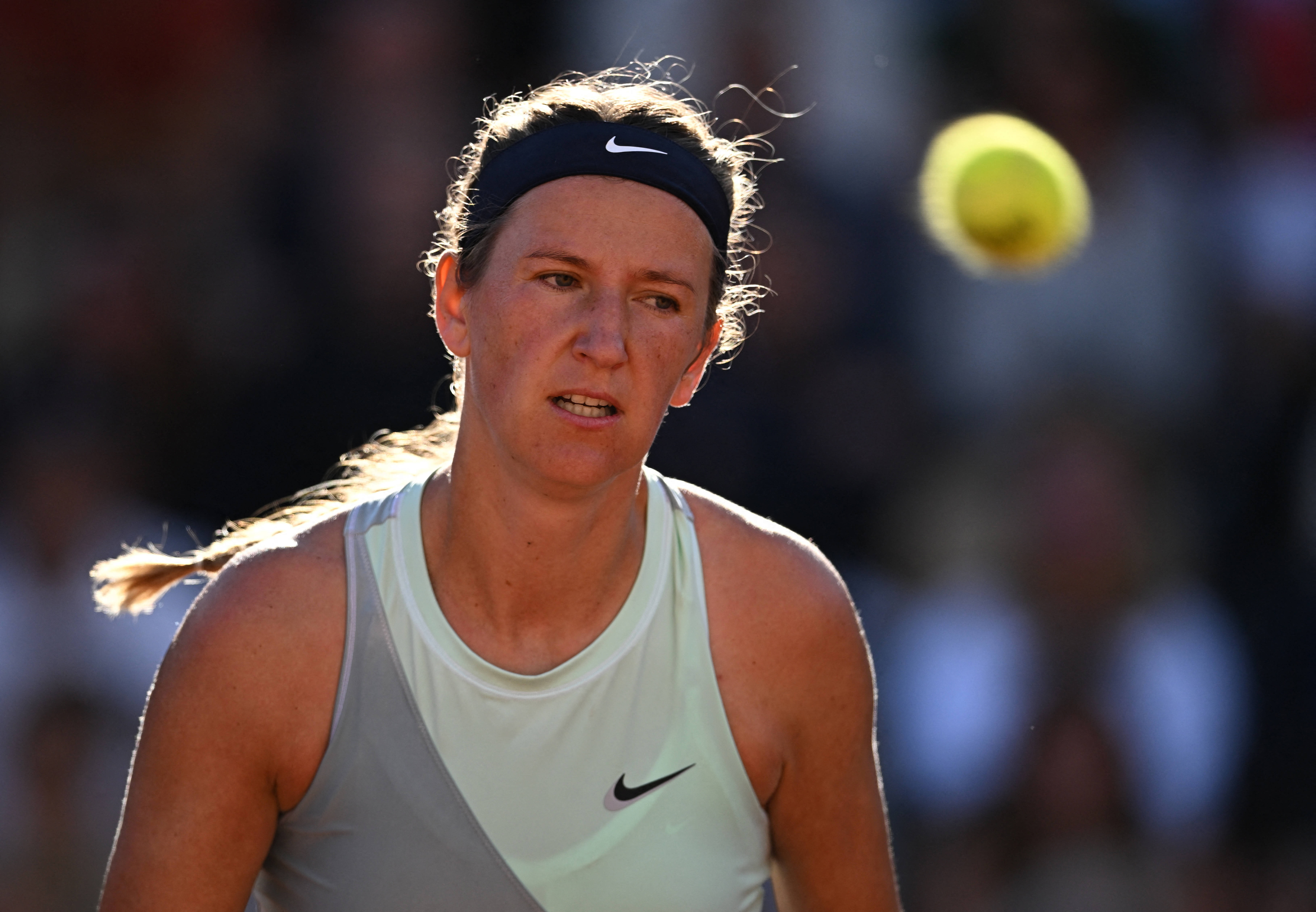 Athletic 桌布 壁紙 — 一位專注的女網球選手在移動中，頭髮飛揚，準備在模糊的人群背景下擊打黃色網球。