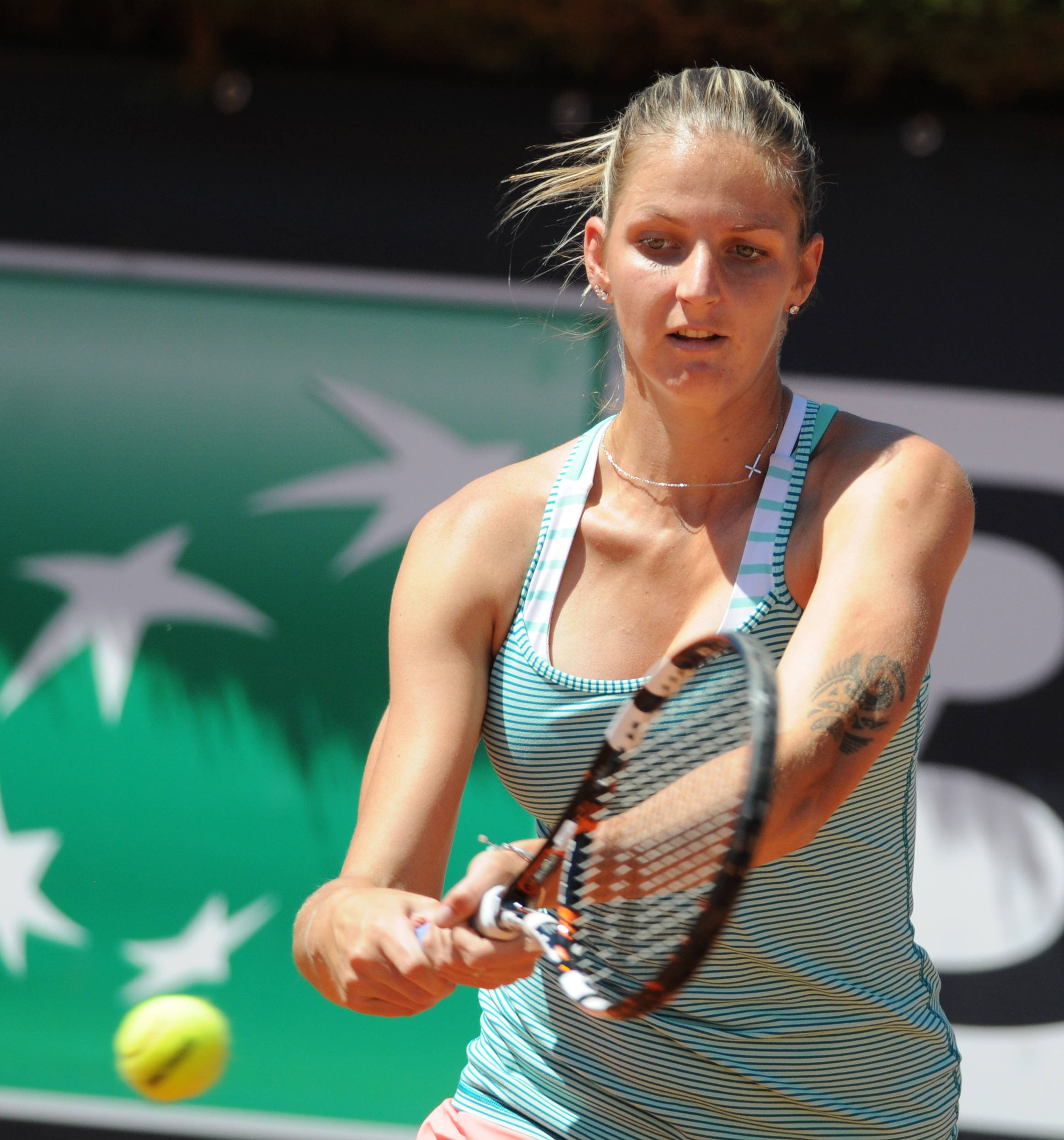 Athlete 桌布 壁紙 — 一位專注的女網球選手揮拍擊向黃色球，背景是帶有白色星星的綠色牆壁。