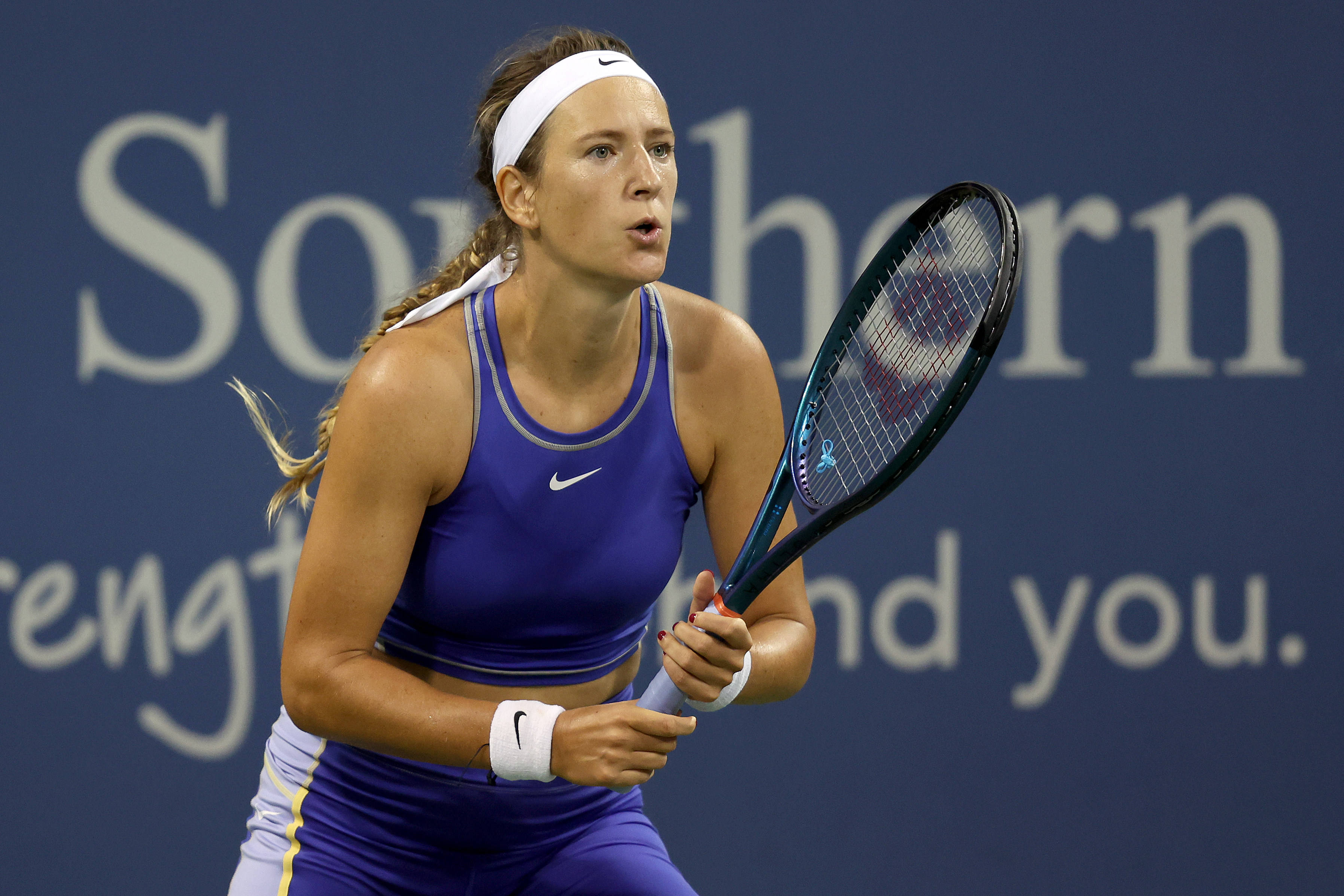 Athletic 桌布 壁紙 — 一位專注的女網球選手穿著紫色Nike服裝，在藍色球場上揮拍比賽。
