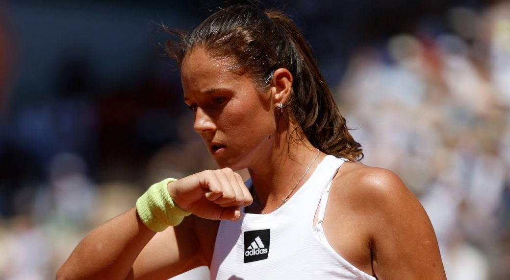 Athletic 桌布 壁紙 — 一位專注的女網球選手身穿白色adidas上衣，在明亮的陽光下比賽中握緊拳頭。