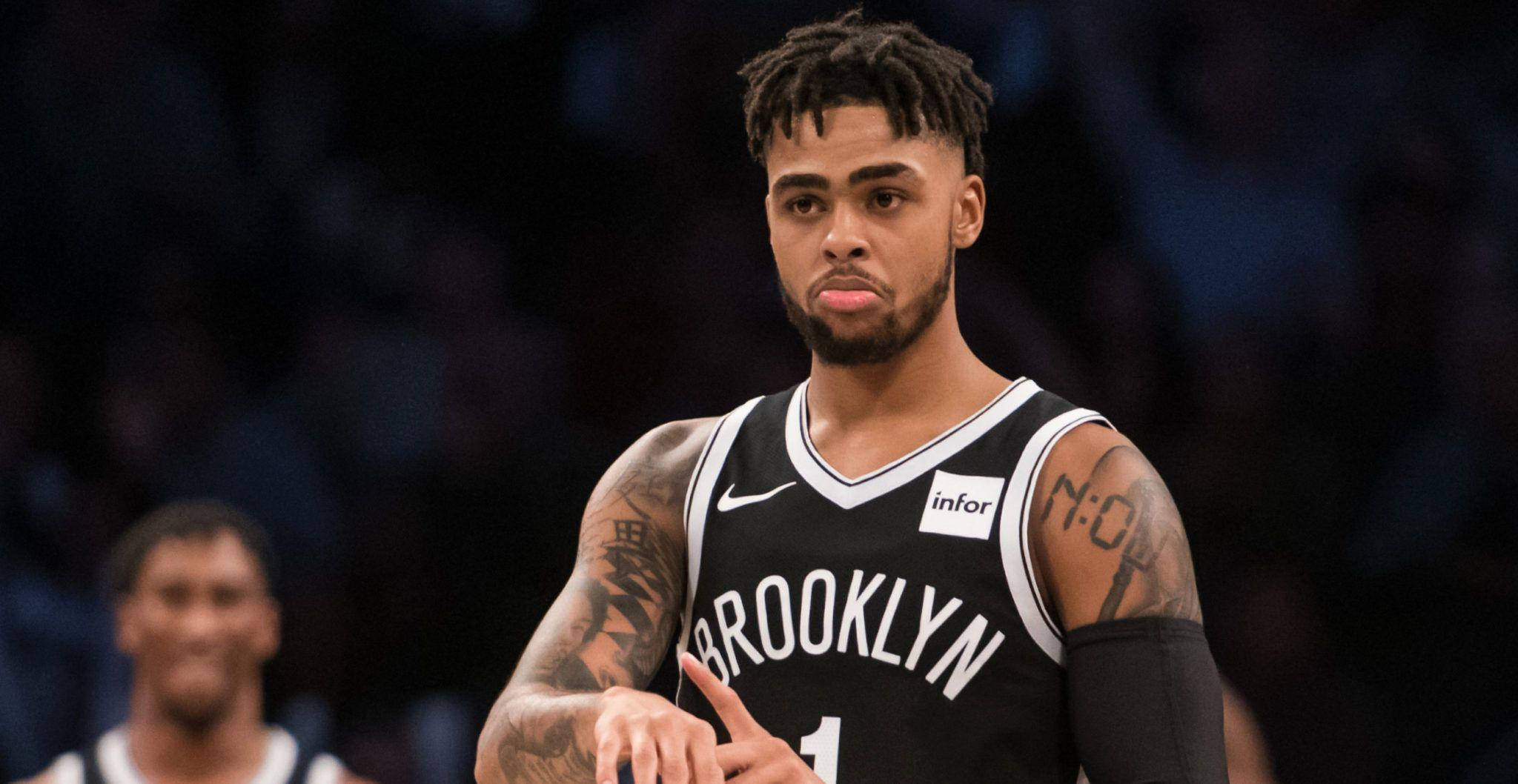 NBA 桌布 壁紙 — 一位專注的布魯克林籃網籃球運動員，身上有刺青，在比賽中於場館燈光下凝視著。