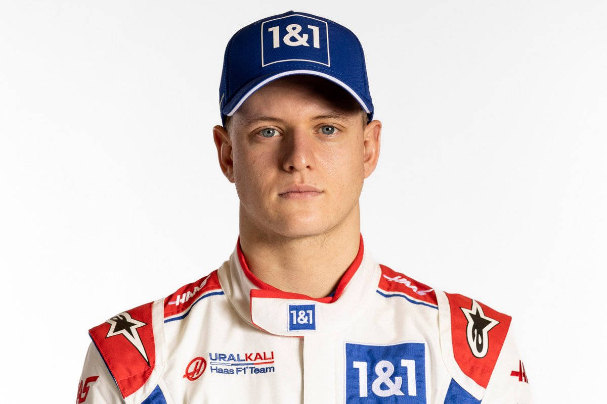 mick schumacher 桌布 壁紙 — 一位專注的年輕賽車手，身穿帶有1&1贊助商標誌的白、紅、藍色Haas F1車隊賽車服，在純白背景前擺姿勢。