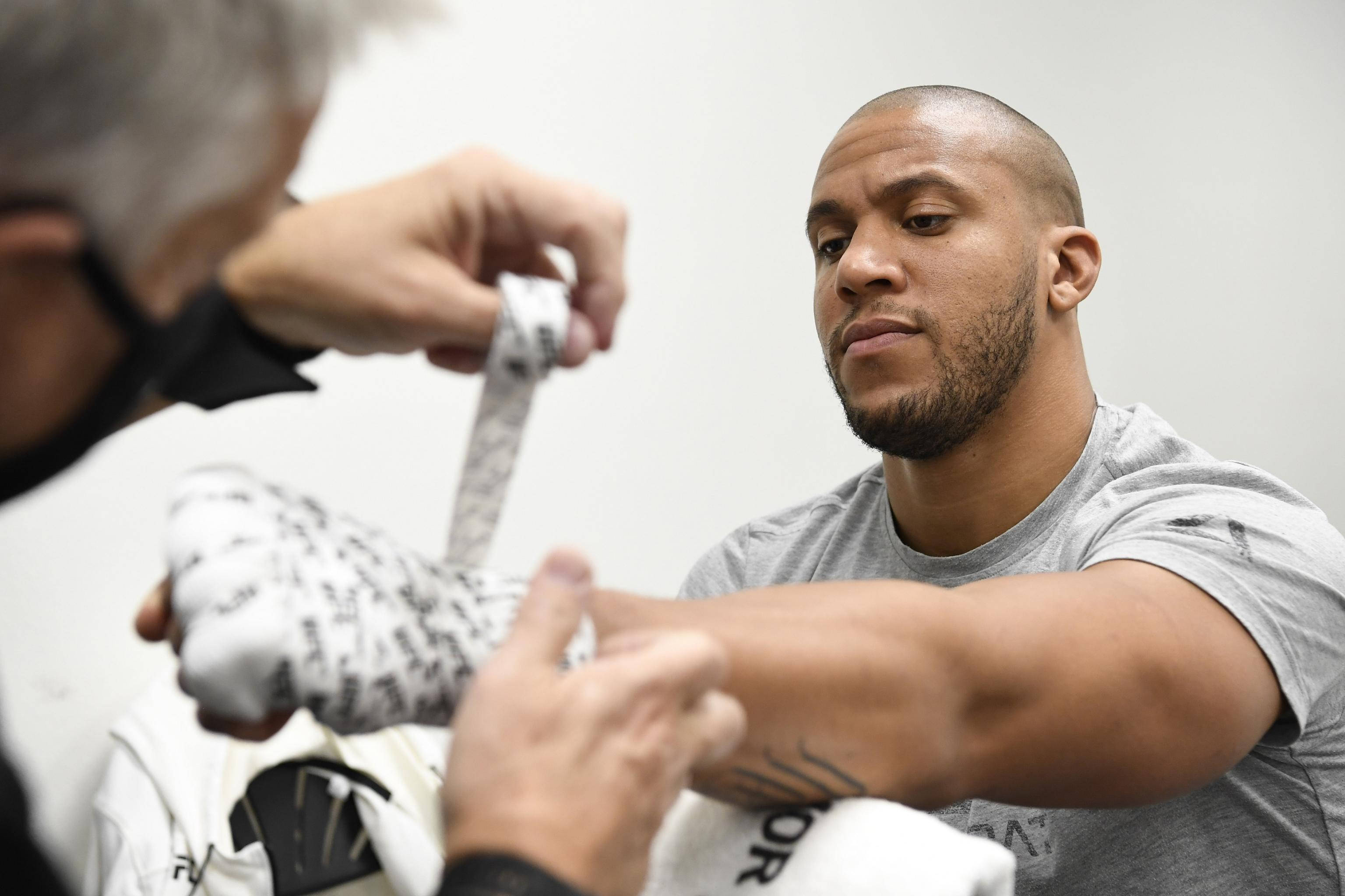 MMA 桌布 壁紙 — 一位專注的拳手在明亮的臨床環境中被教練包裹著手。