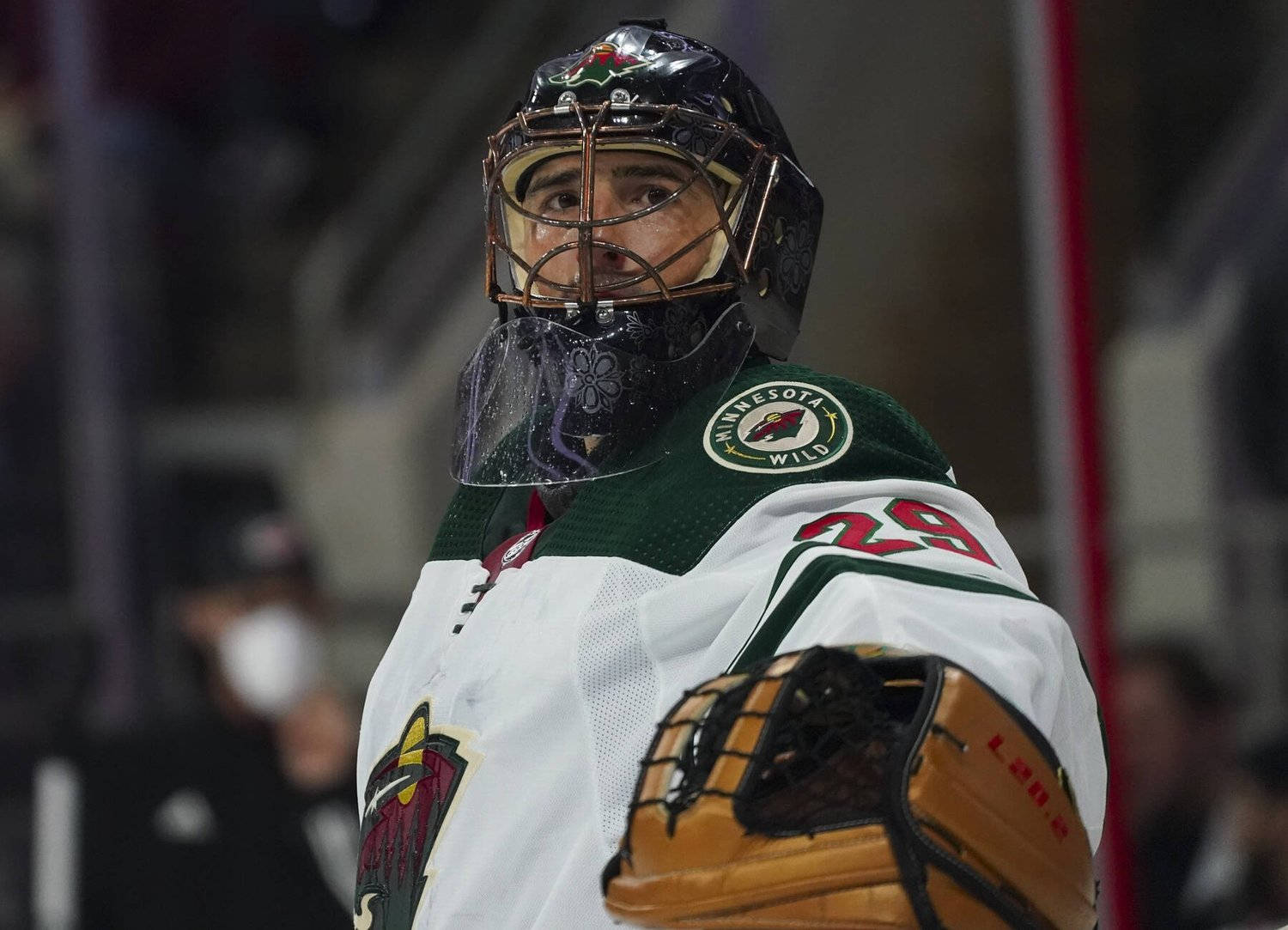 hockey 桌布 壁紙 — 一位專注的明尼蘇達荒野冰球守門員，身穿全套裝備，在場館燈光下比賽中專注地凝視。
