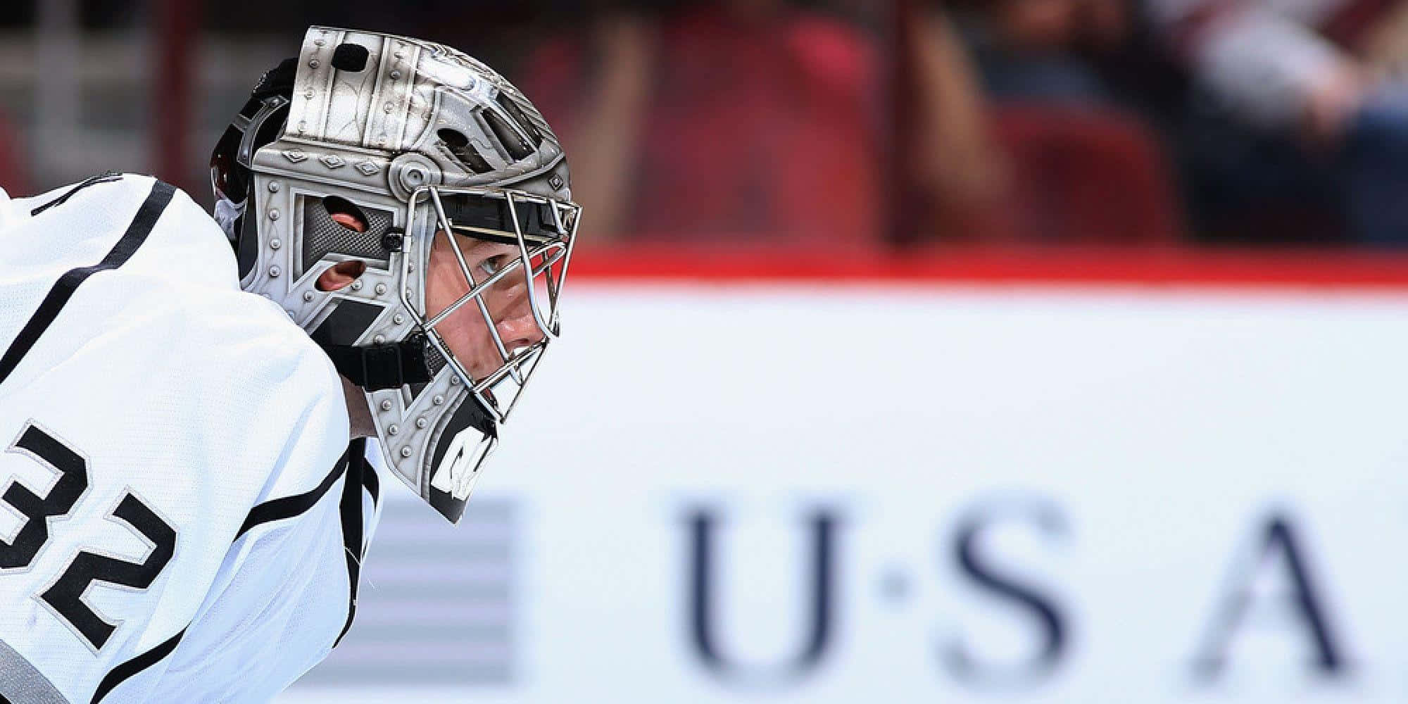 Jonathan Quick 桌布 壁紙 — 一位專注的曲棍球守門員，身穿白色和黑色裝備，背號32，在美國隊比賽中凝視前方。