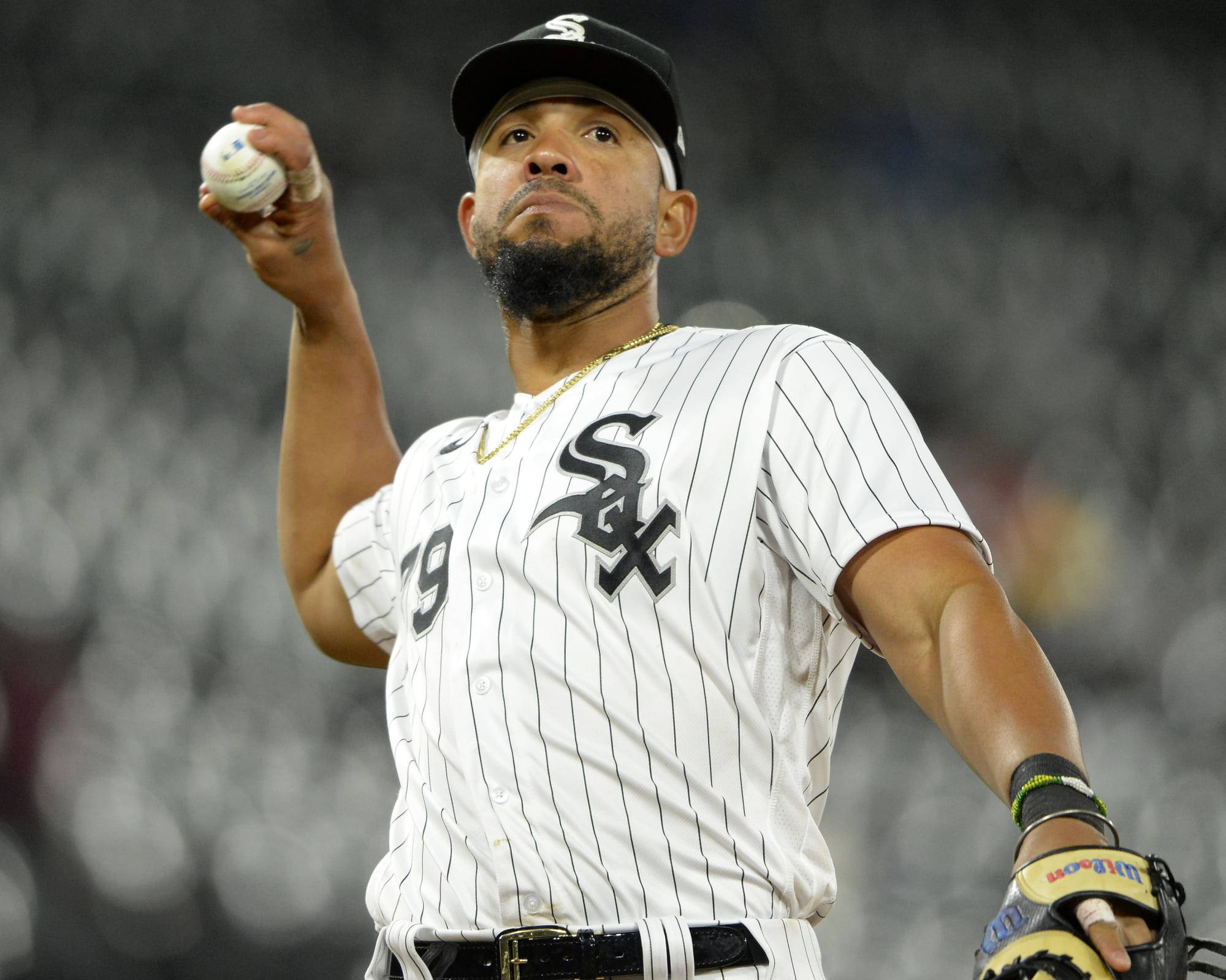 jose abreu 桌布 壁紙 — 一位專注的棒球投手身穿白色細條紋Sox球衣，在球場燈光下準備投球。
