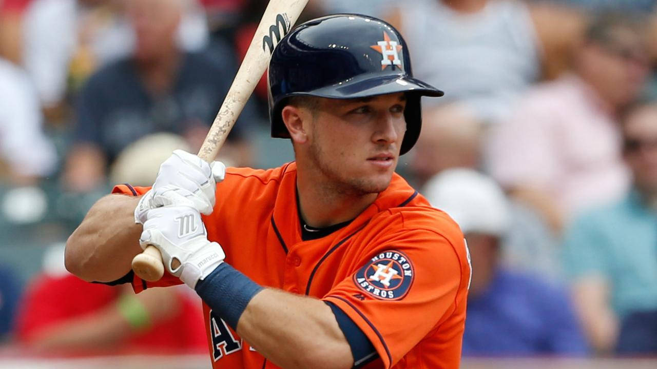 Bregman 桌布 壁紙 — 一位專注的棒球運動員身穿橙色休士頓太空人隊制服，在日間比賽中揮棒中途握緊球棒，背景有模糊的觀眾。