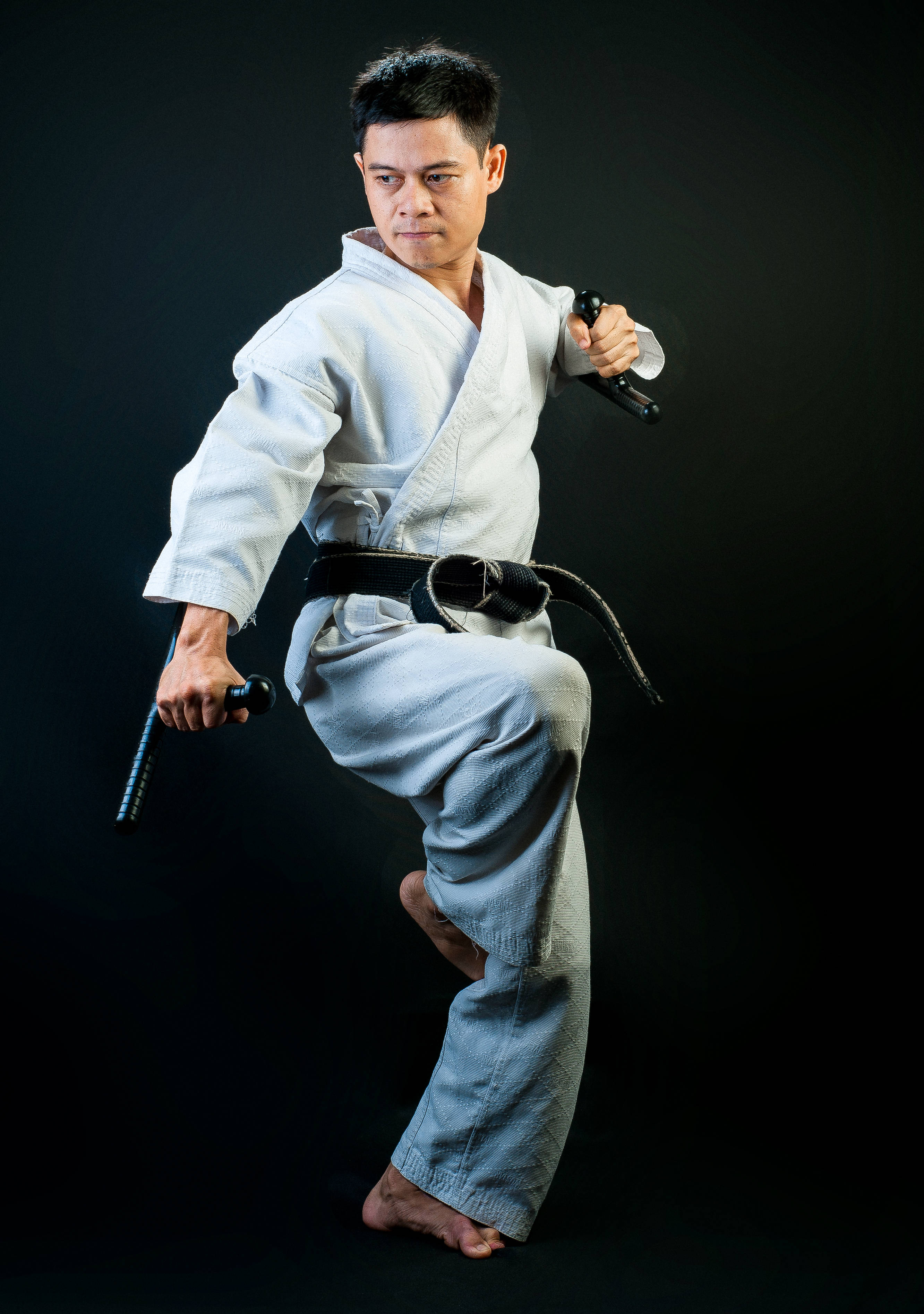 Judo 桌布 壁紙 — 一位專注的武術家身穿白色道服，繫著黑帶，在純黑背景下動態出擊。