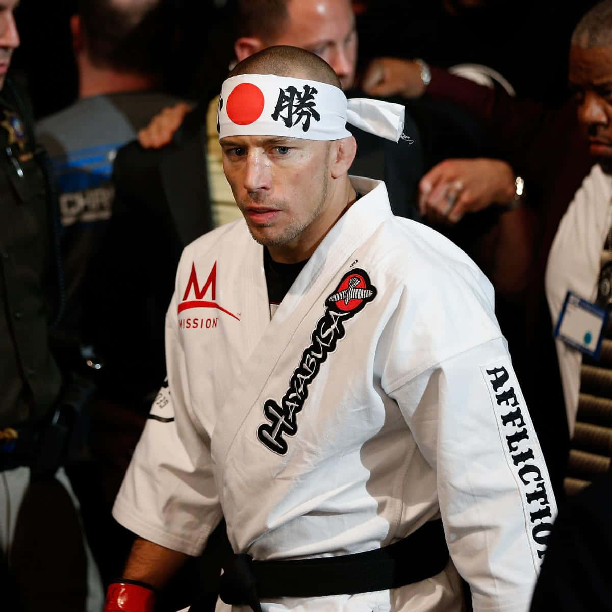 martial arts 桌布 壁紙 — 一位專注的武術家身穿白色道服、黑色腰帶和頭帶，在昏暗的競技場中準備就緒。