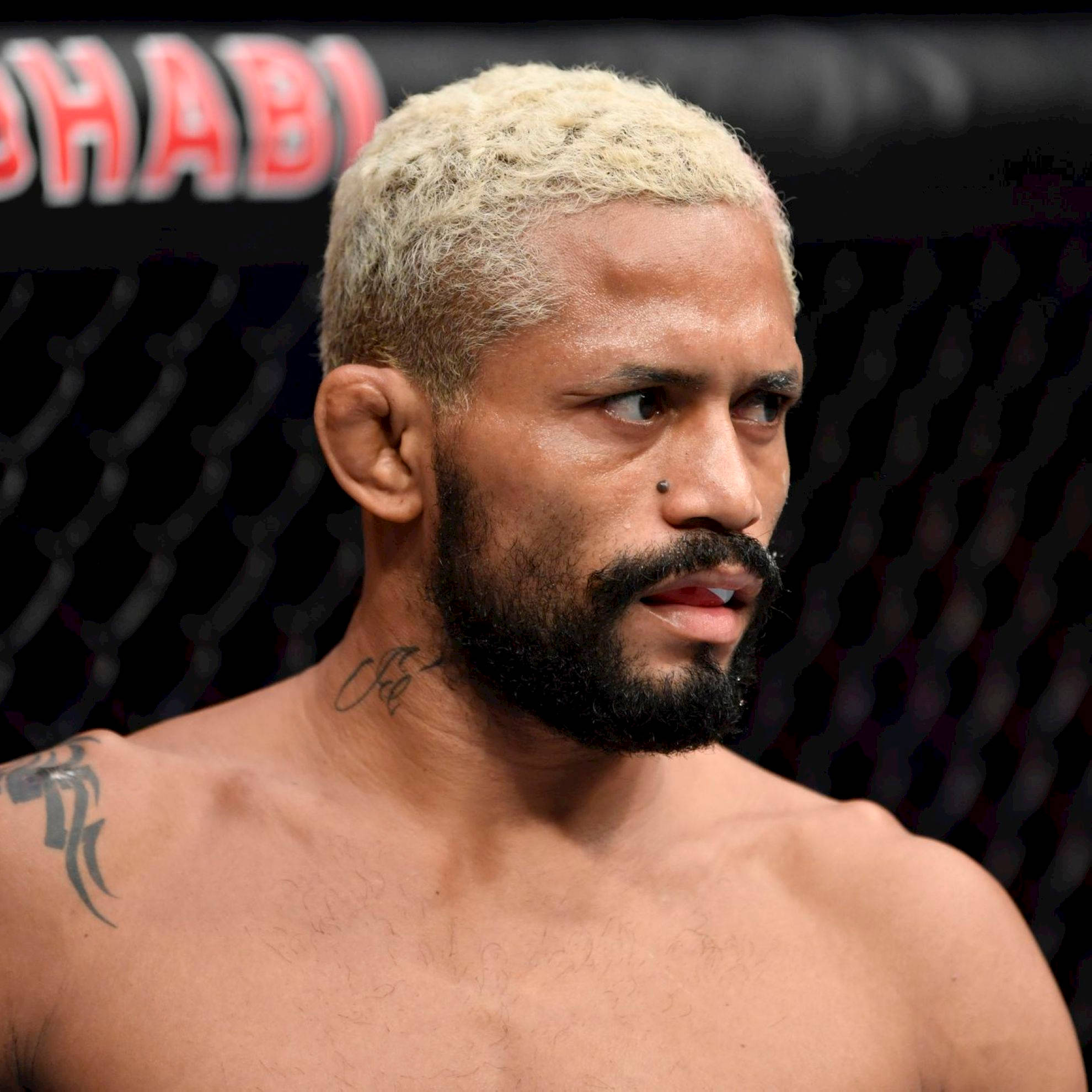 MMA 桌布 壁紙 — 一位專注的混合武術家，漂白金髮和刺青，在籠中戰鬥時凝視著。