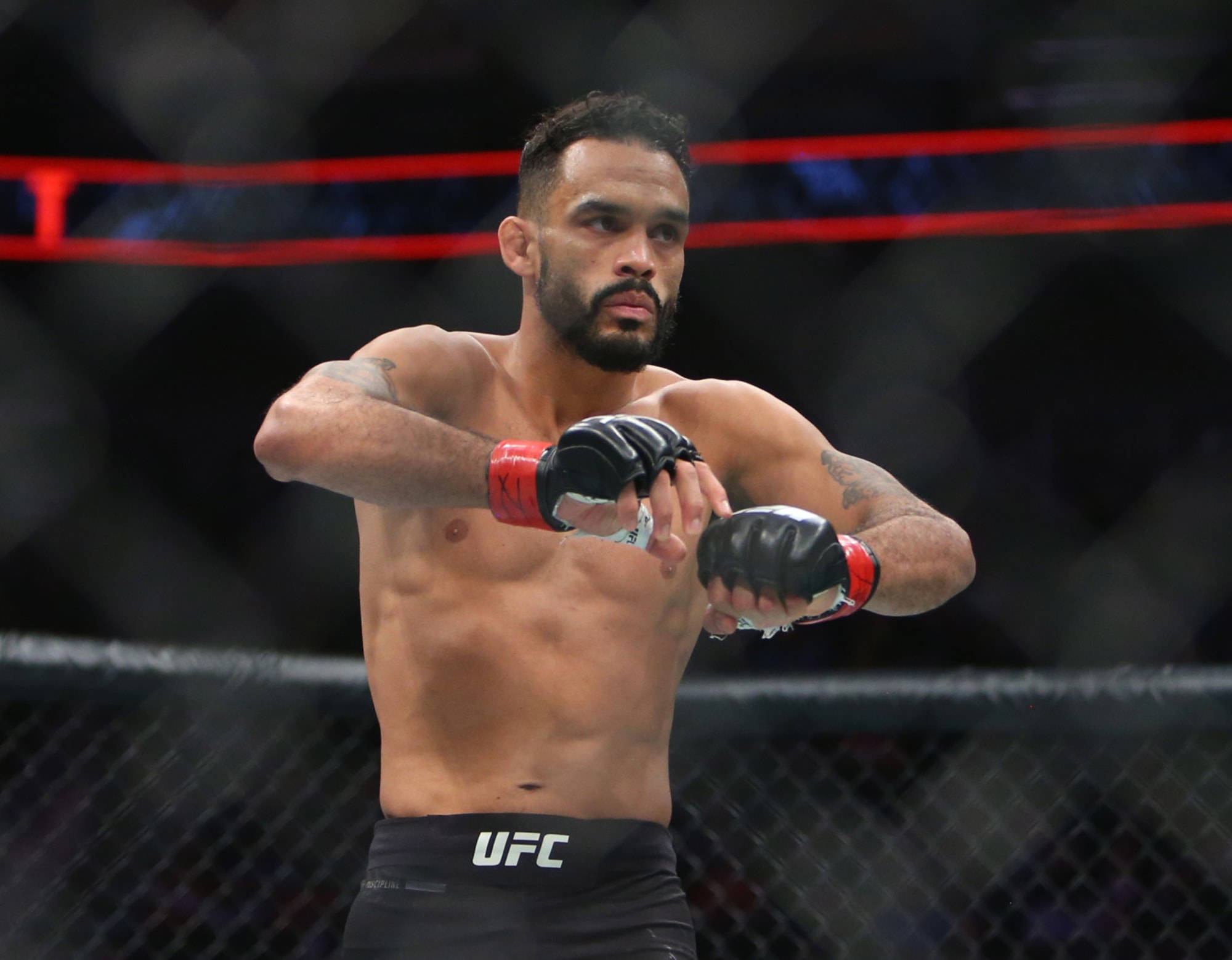UFC 桌布 壁紙 — 一位專注的混合武術選手在UFC八角籠中，以強烈的決心準備戰鬥。